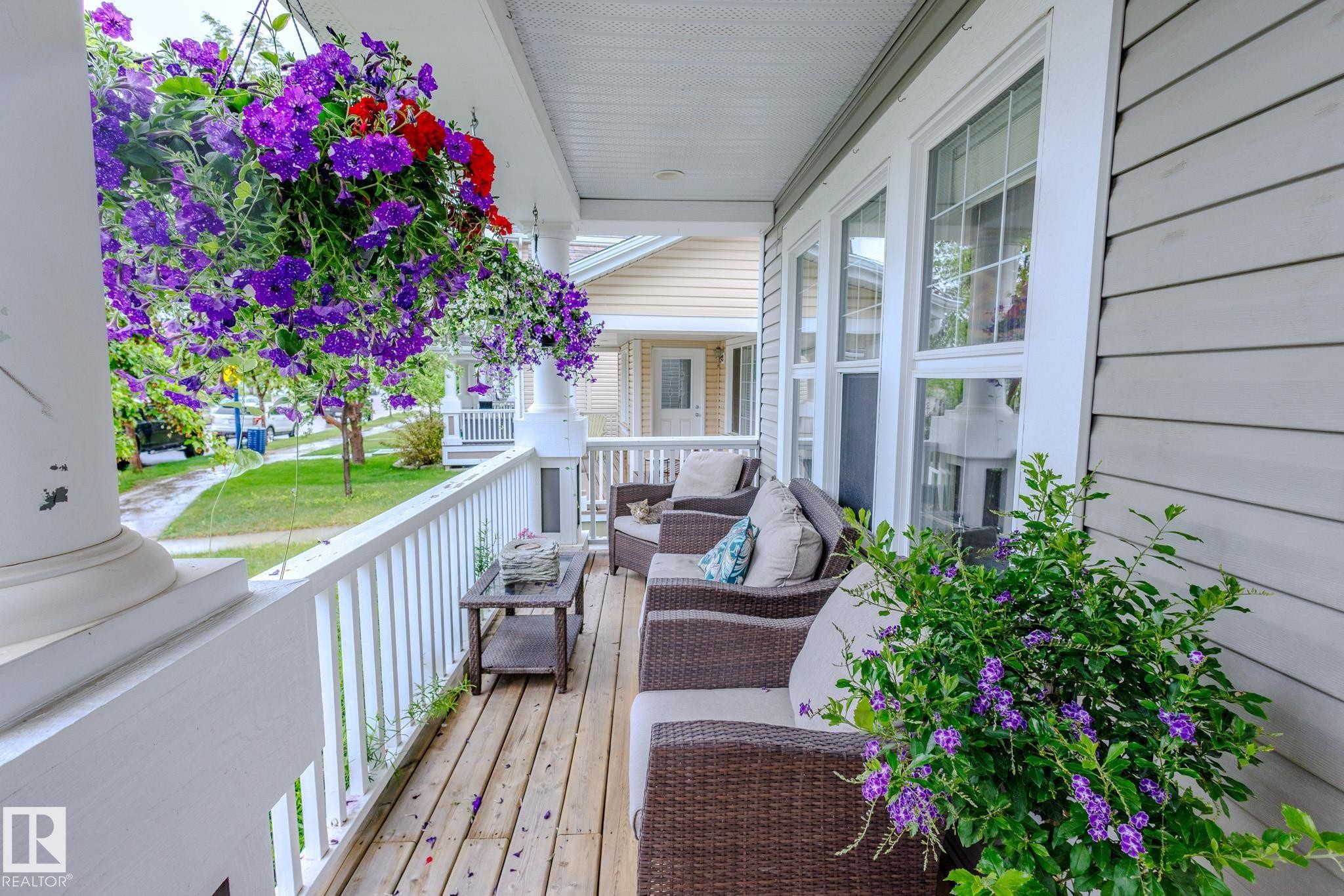 Inviting porch featuring wood-finish flooring, white spindle railing, and a slatted ceiling - 7207 14A Avenue, Edmonton, AB - Outdoor With Deck Patio Veranda With Exterior