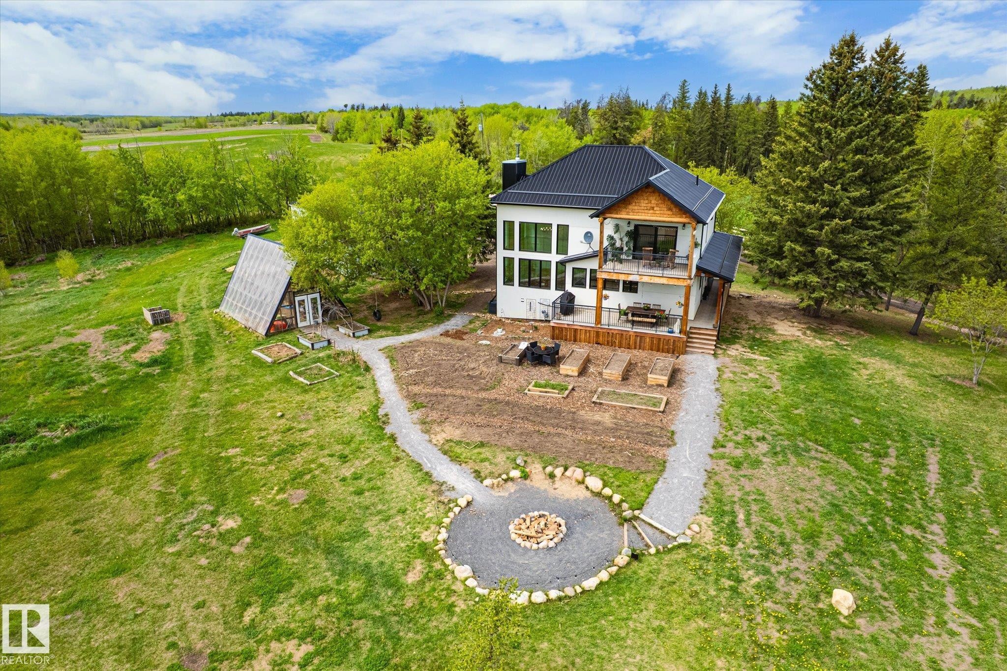 Contemporary white-sided residence with a black roof, featuring a multi-level wooden deck - 59102 Rge Road 234, Rural Westlock County, AB