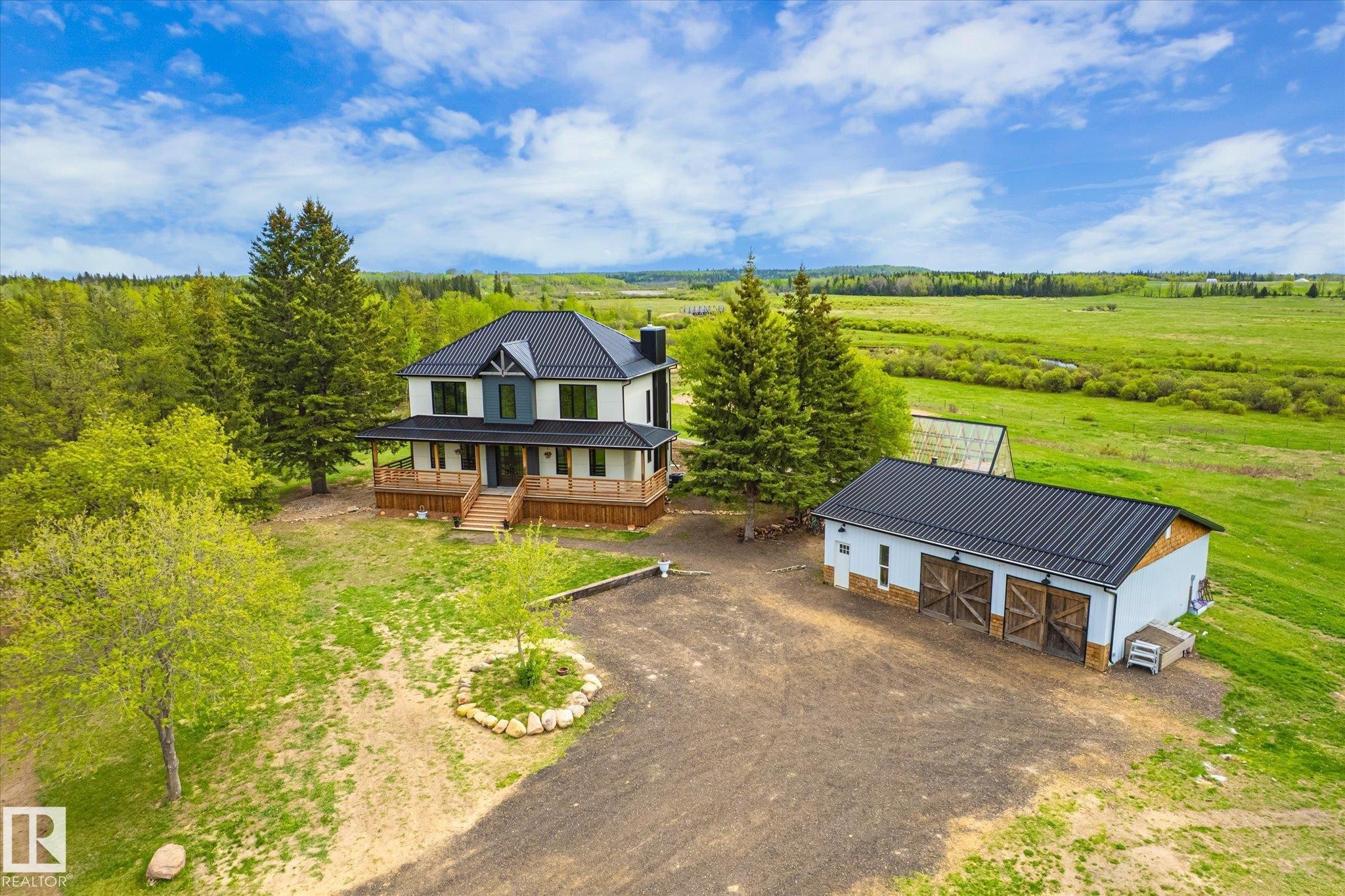 Two-story residence featuring an expansive wrap-around porch and dark metal roofing - 59102 Rge Road 234, Rural Westlock County, AB