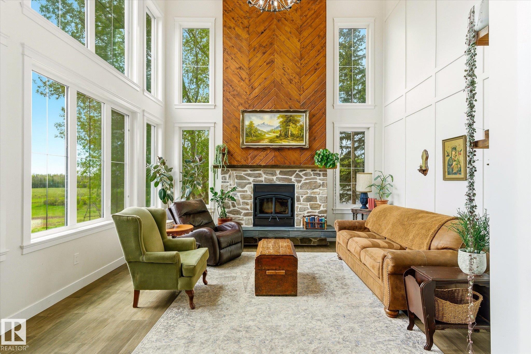 Two-story living room featuring a stone fireplace with a wood-finish herringbone accent wall - 59102 Rge Road 234, Rural Westlock County, AB