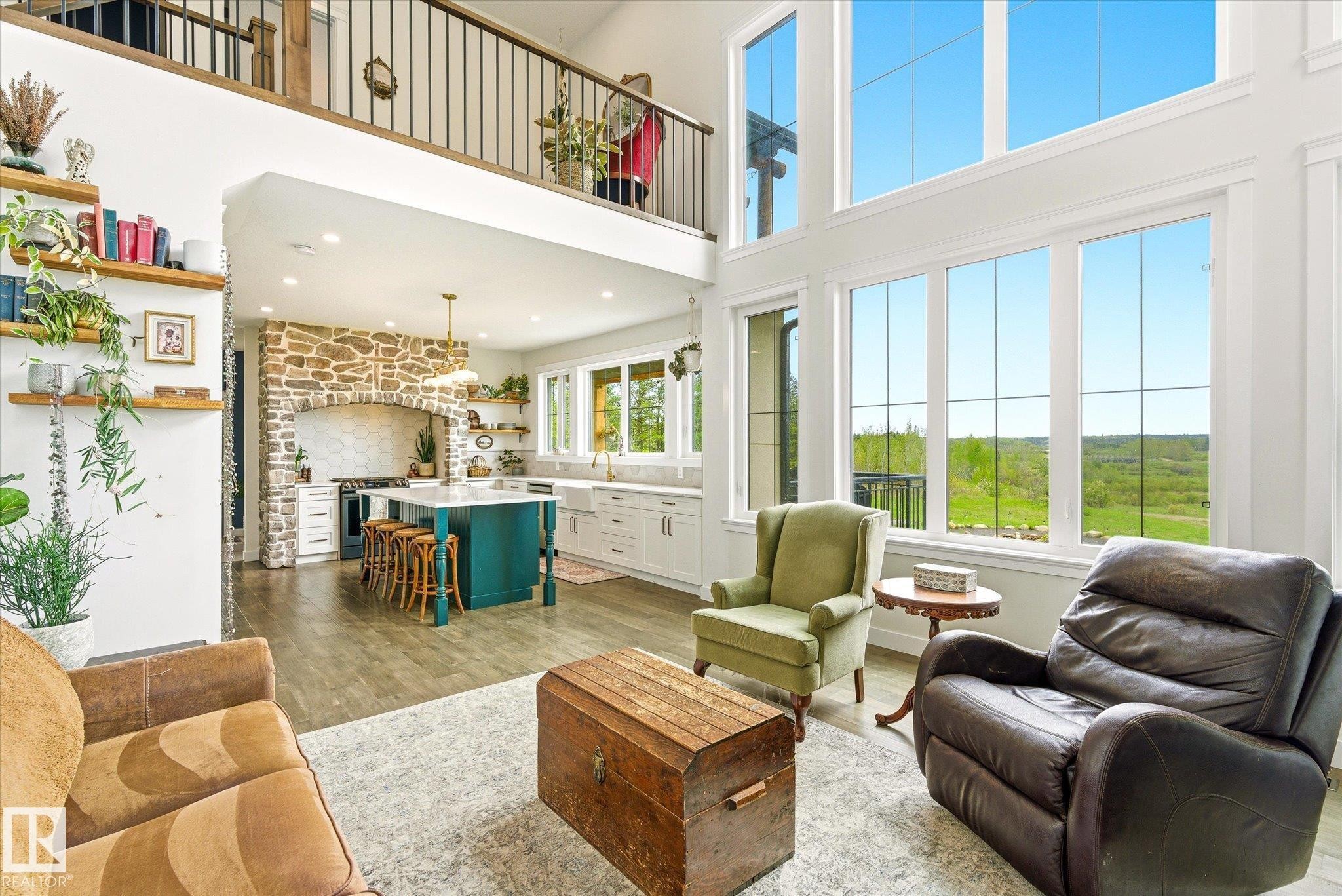Two-story living area with expansive floor-to-ceiling windows, wood-finish flooring, and a second-story balcony overlooking the space - 59102 Rge Road 234, Rural Westlock County, AB