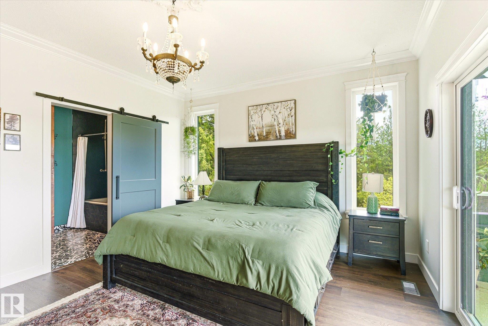 Spacious room featuring wood-finish flooring, a decorative chandelier, and a sliding barn door - 59102 Rge Road 234, Rural Westlock County, AB