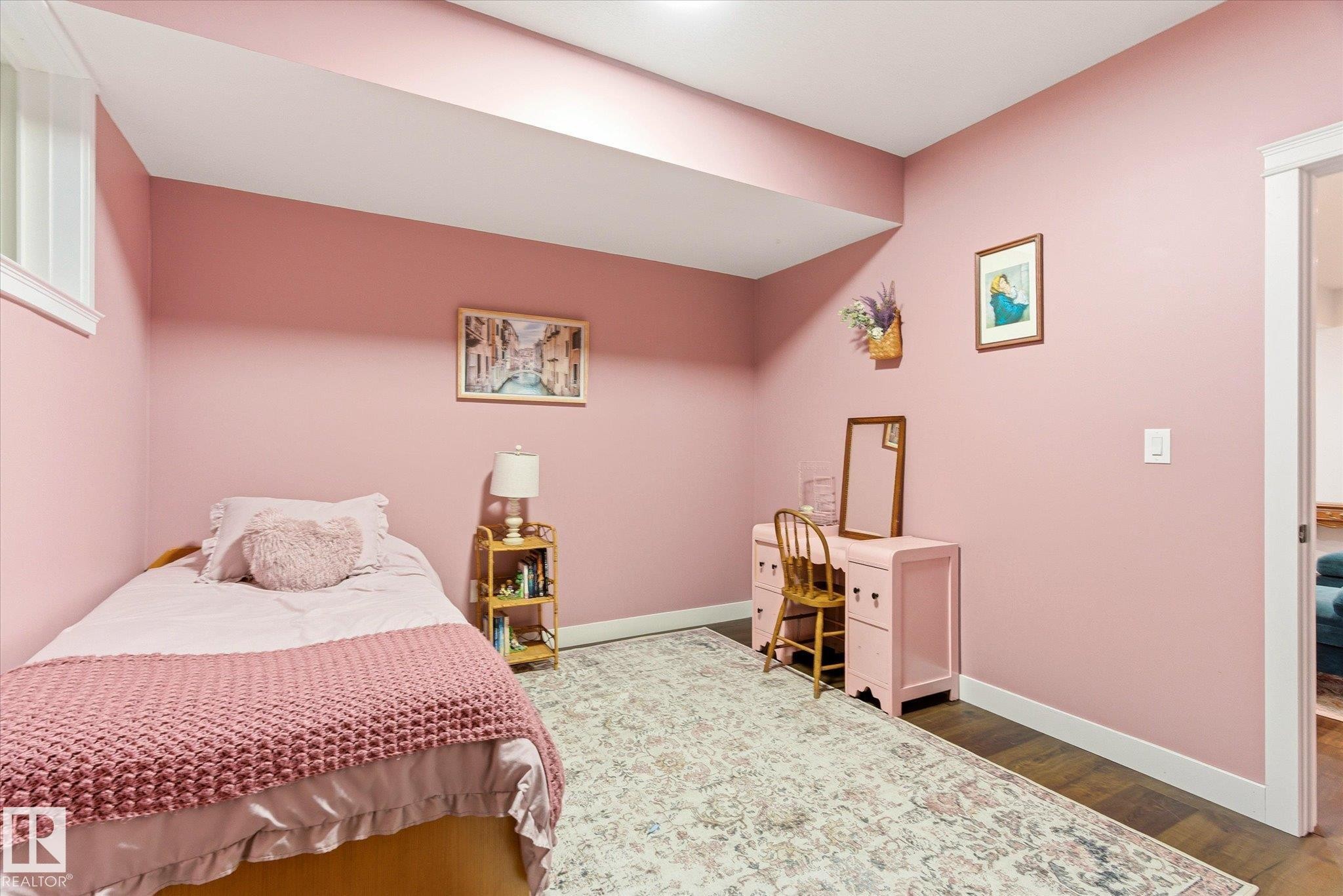Versatile room featuring dark wood-finish flooring, light pink walls, white baseboards, and a white trim window - 59102 Rge Road 234, Rural Westlock County, AB