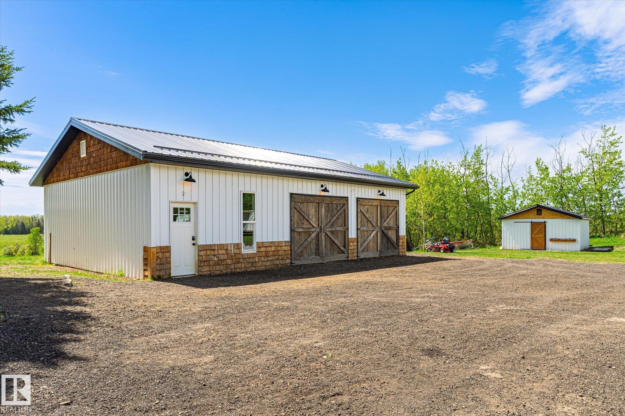 Detached outbuilding featuring a metal roof, white vertical siding, and a stone veneer base - 59102 Rge Road 234, Rural Westlock County, AB