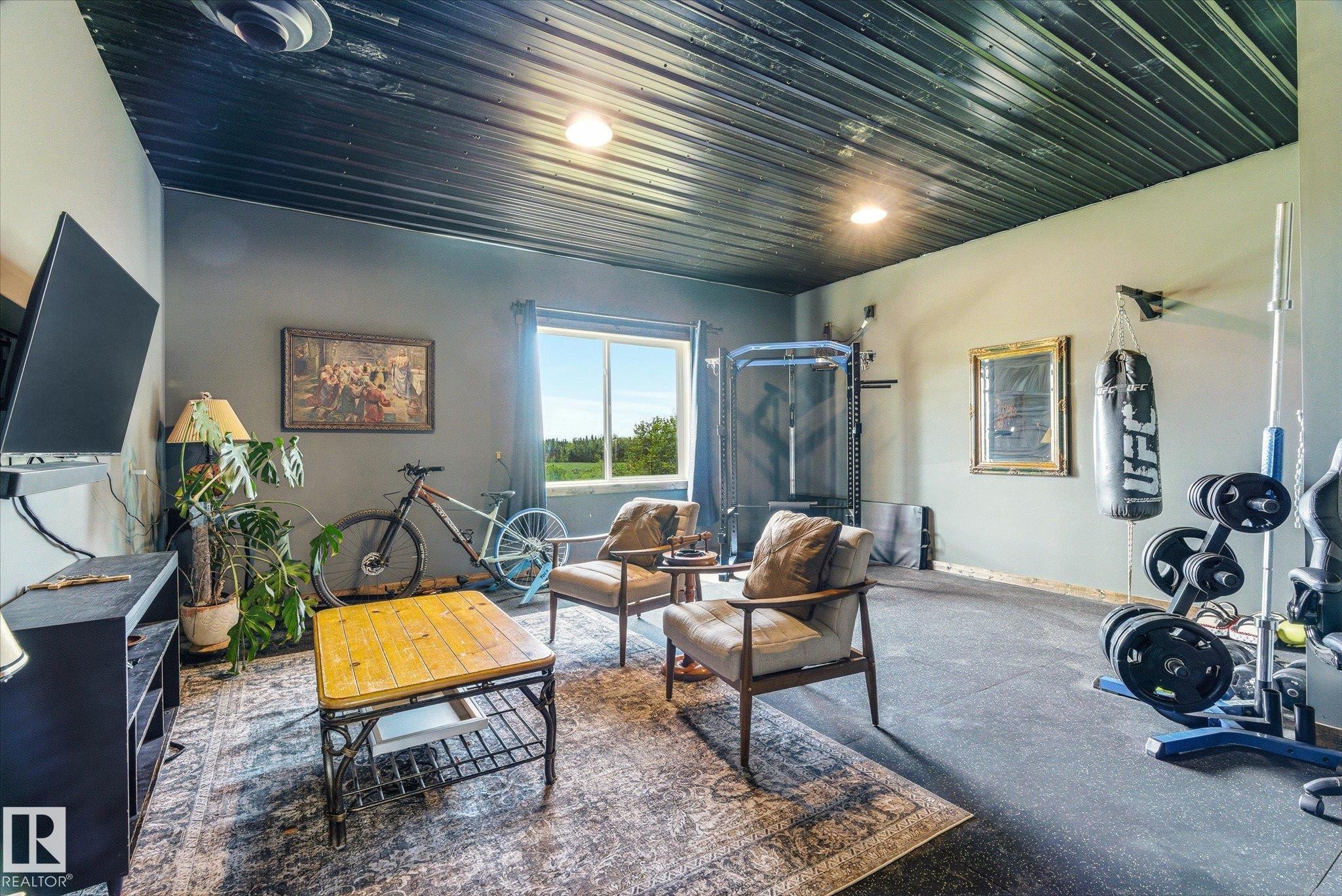 Versatile room featuring a window overlooking expansive outdoor scenery, recessed lighting, a dark corrugated ceiling, and a large area rug complementing the wall color - 59102 Rge Road 234, Rural Westlock County, AB