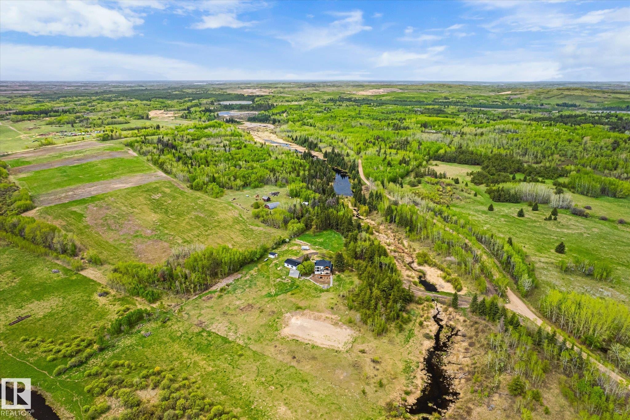 Expansive rural property featuring broad green fields, abundant mature trees, a meandering stream, and multiple small ponds - 59102 Rge Road 234, Rural Westlock County, AB