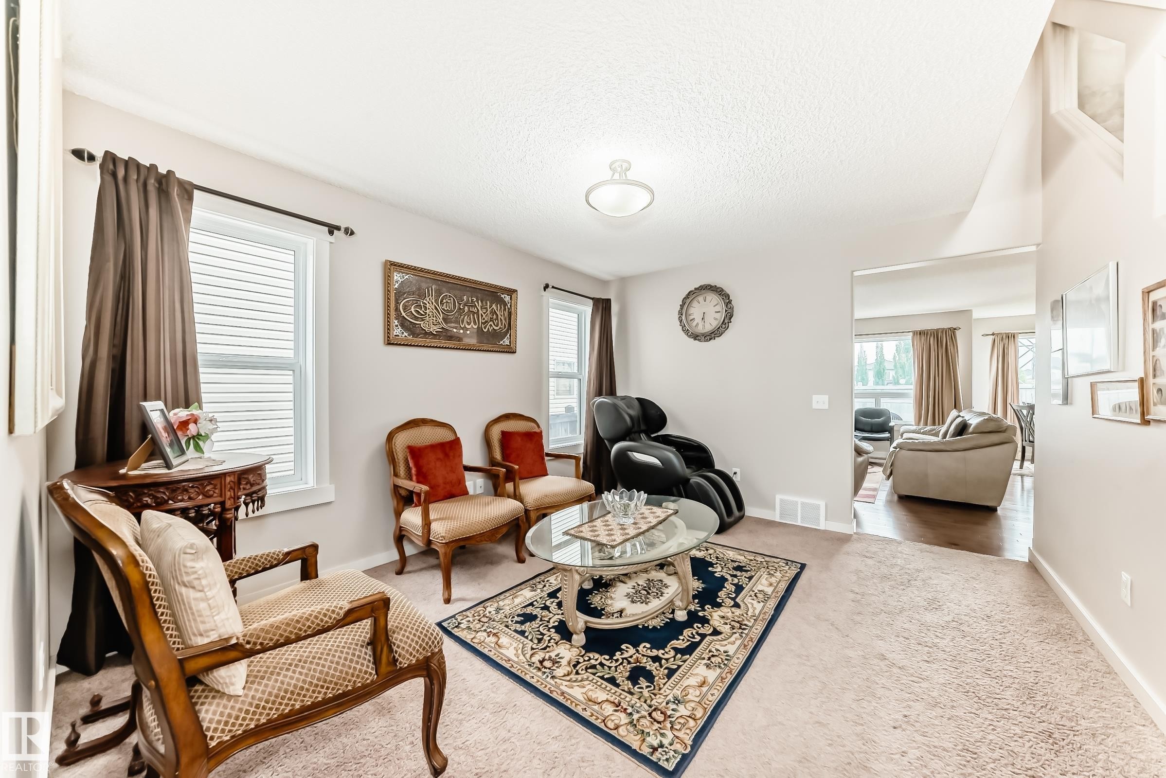 Carpeted living area featuring multiple windows with blinds, a circular semi-flush mount ceiling light, and light-toned walls - 2808 36 Avenue, Edmonton, AB