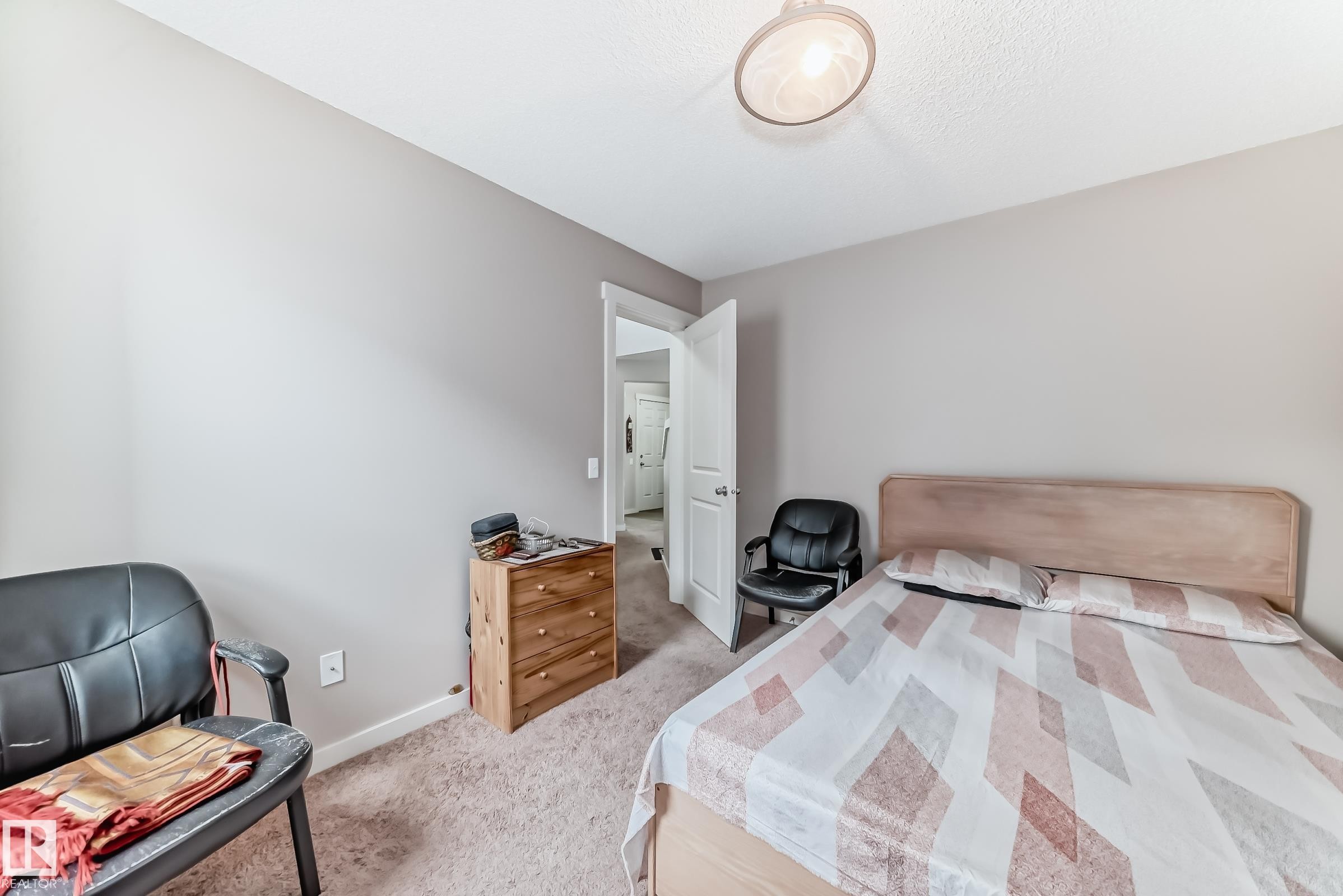 Neutral-toned bedroom with textured carpeting and a ceiling-mounted light fixture - 2808 36 Avenue, Edmonton, AB