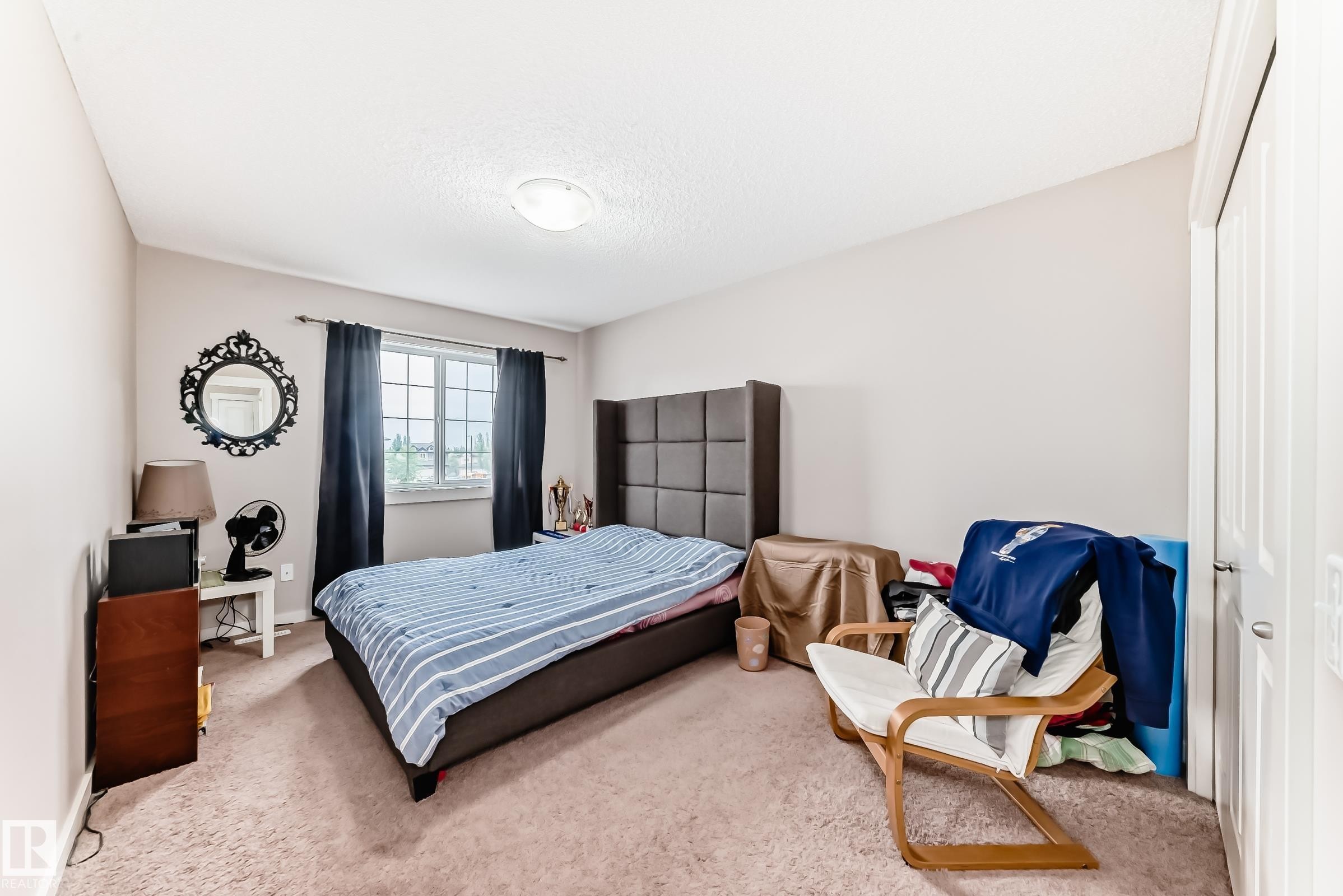 Carpeted bedroom featuring a large window with privacy coverings, a built-in closet with a white panel door, and a flush-mount ceiling light fixture - 2808 36 Avenue, Edmonton, AB
