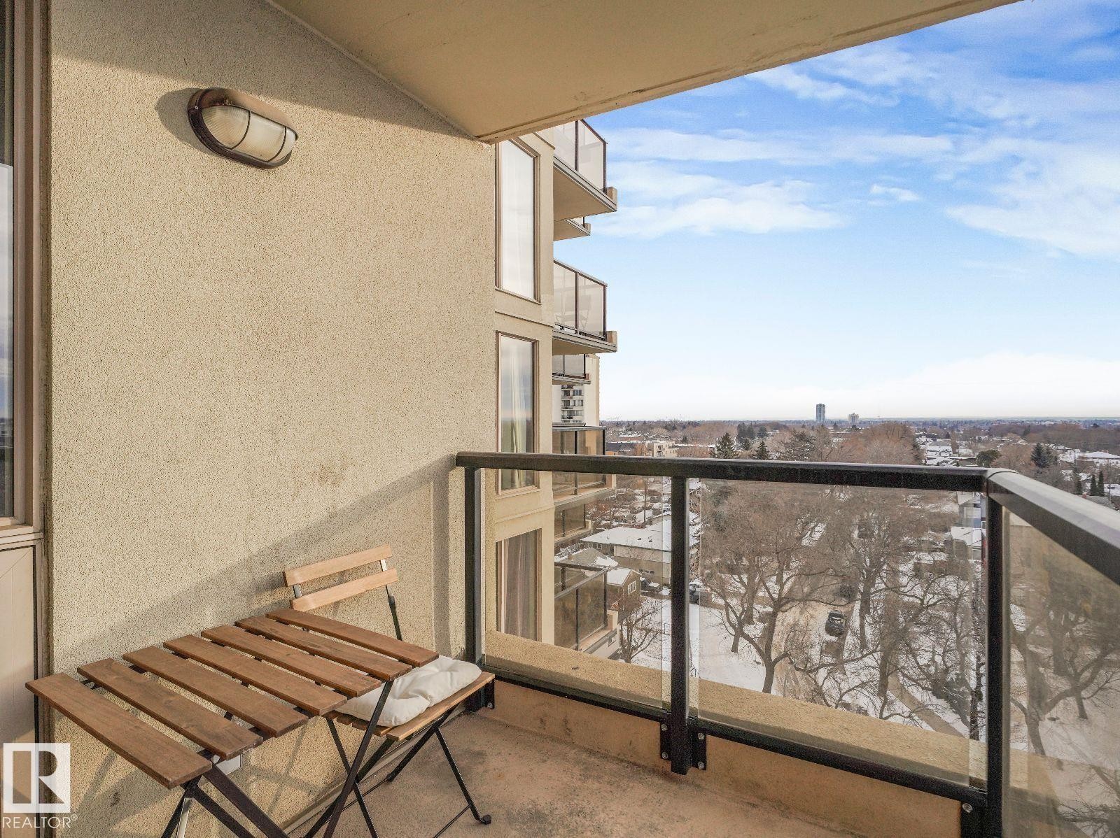 Private balcony featuring a stucco exterior, contemporary glass and metal railing, and an exterior light fixture - 806 10149 Saskatchewan Drive, Edmonton, AB