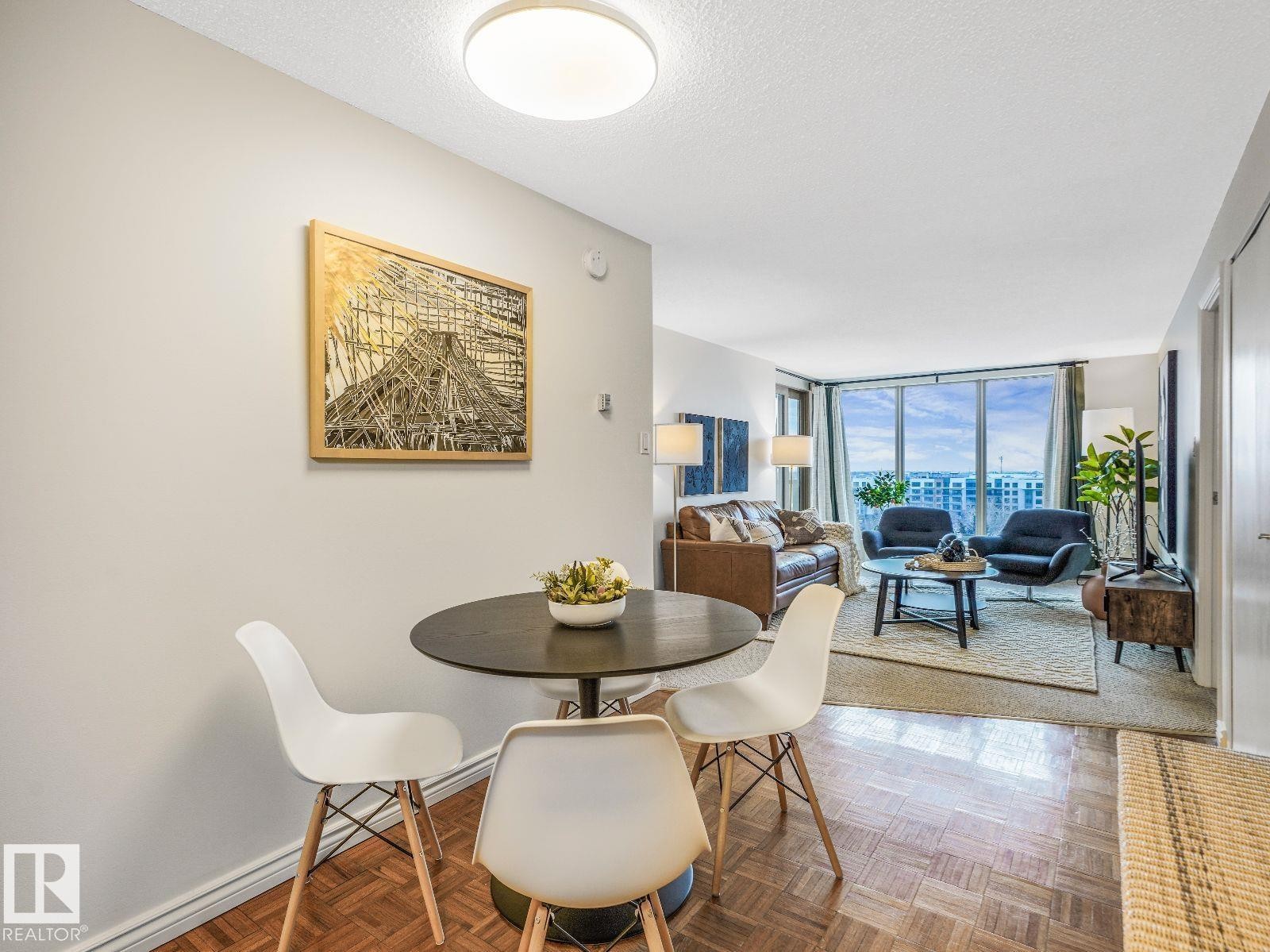 Parquet flooring extending into the open-concept living area, featuring a large window with city scenery - 806 10149 Saskatchewan Drive, Edmonton, AB