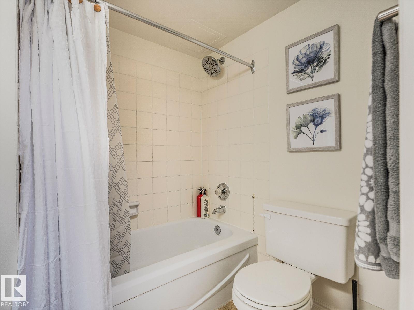 Bathtub with white subway tile surround, chrome fixtures, and a ceiling-mounted showerhead - 806 10149 Saskatchewan Drive, Edmonton, AB