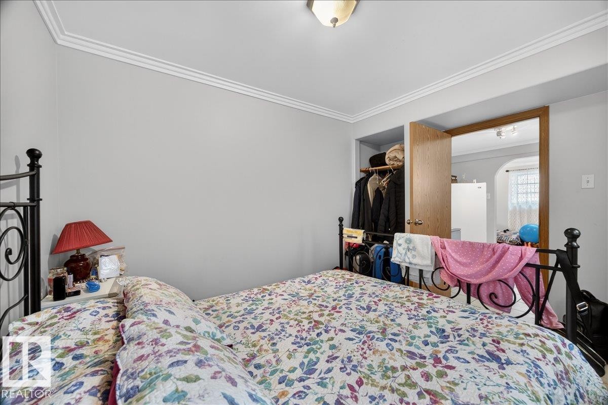 Neutral-toned bedroom with crown molding, featuring a built-in closet with an adjacent doorway - 5108 138A Avenue, Edmonton, AB