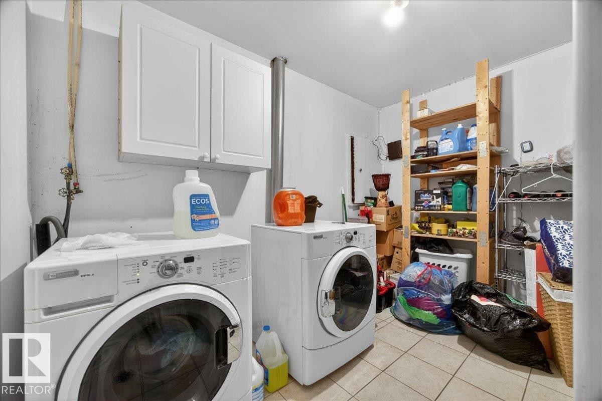 Dedicated laundry area featuring tile flooring, white wall-mounted cabinetry, and ample shelving for organization - 5108 138A Avenue, Edmonton, AB