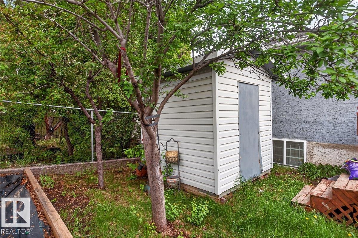 Detached shed featuring horizontal siding and a solid door, surrounded by mature trees - 5108 138A Avenue, Edmonton, AB