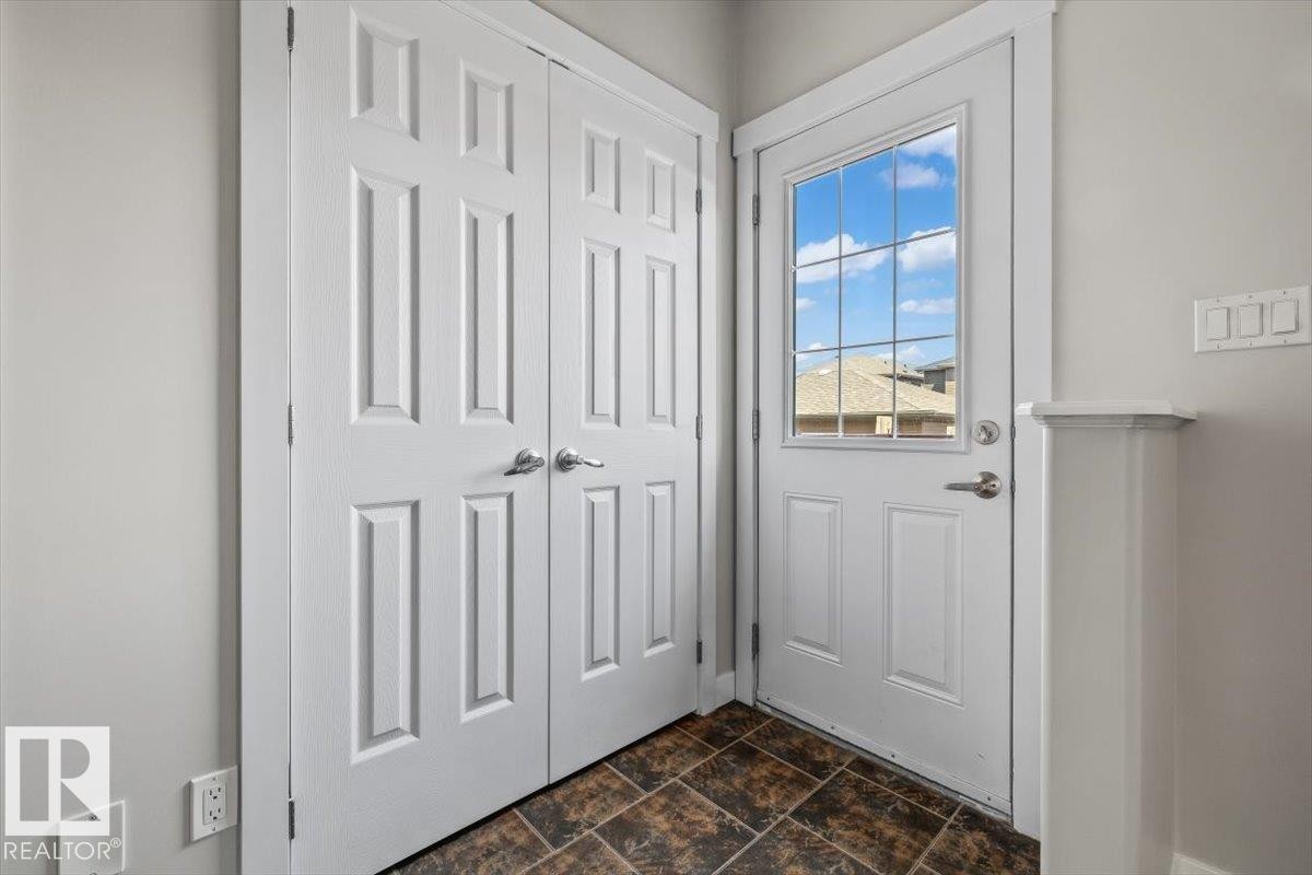 Entryway featuring a paneled door with grid window, a double bi-fold closet, and durable tile flooring - 356 Pioneer Road, Spruce Grove, AB