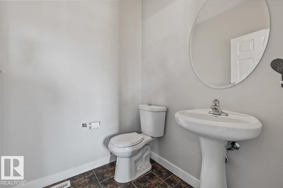 Pedestal sink with chrome faucet and circular mirror - 356 Pioneer Road, Spruce Grove, AB