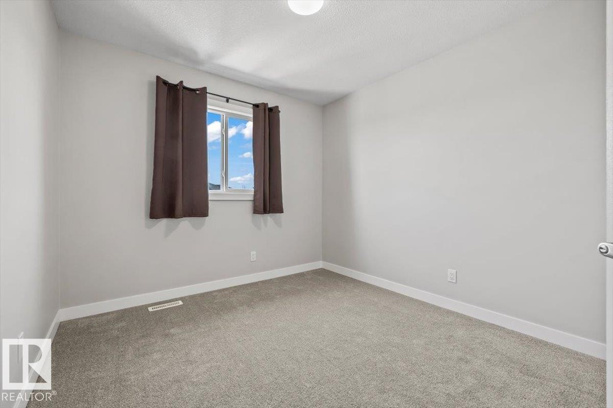 Neutral gray wall finish, plush gray carpeting, white trim, and a window with brown drapes - 356 Pioneer Road, Spruce Grove, AB