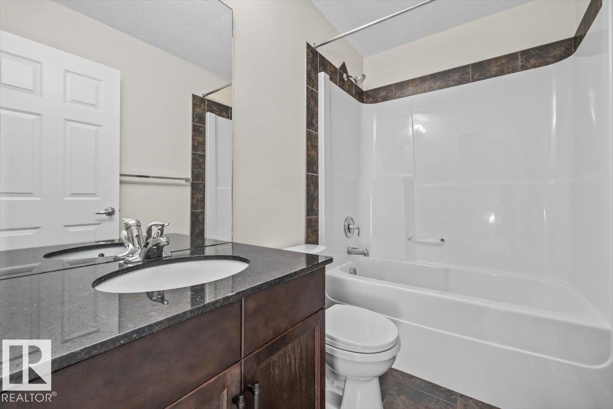 Bathroom featuring a dark wood-finish vanity with an undermount sink and a dark stone countertop - 356 Pioneer Road, Spruce Grove, AB