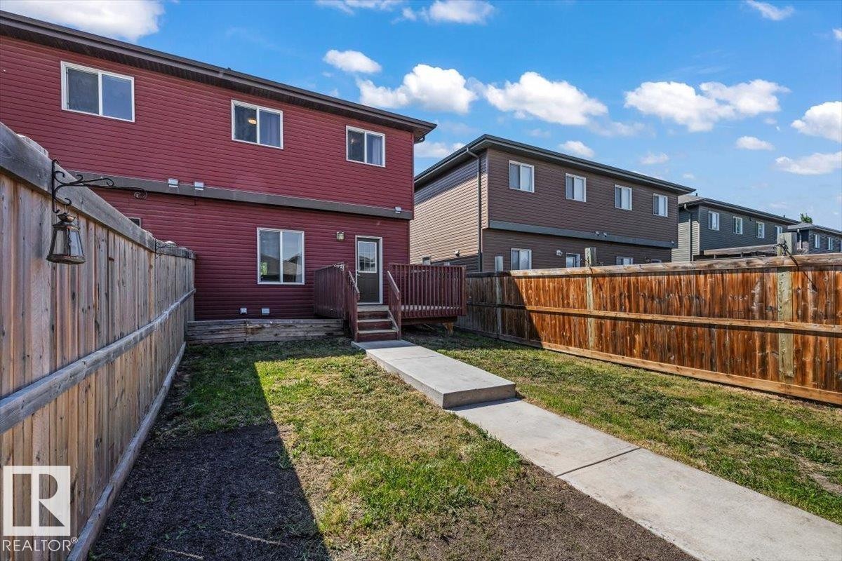 Red siding exterior with multiple windows, a rear deck, and a privacy fence - 356 Pioneer Road, Spruce Grove, AB