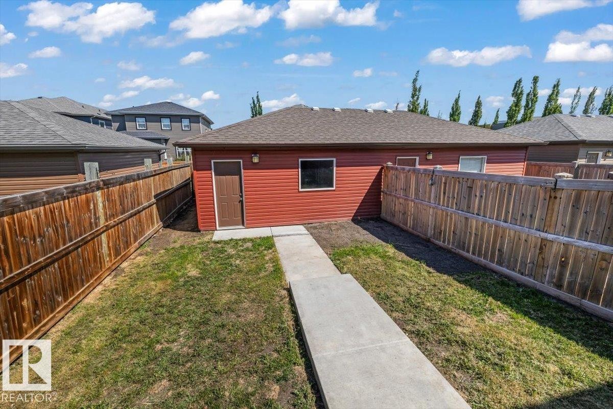 Detached garage featuring red siding, a brown entry door, and multiple windows - 356 Pioneer Road, Spruce Grove, AB