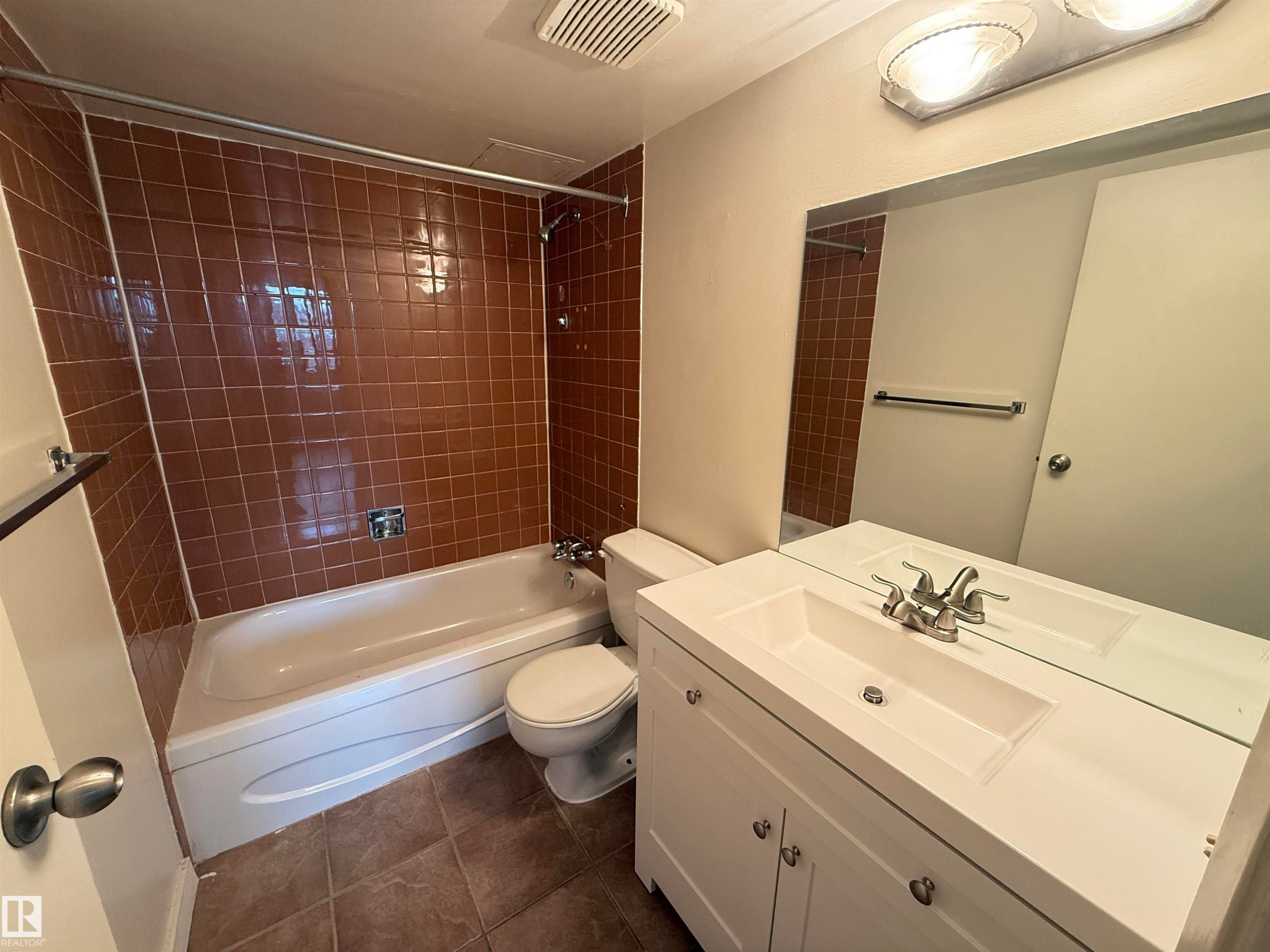 Bathroom featuring a white vanity with integrated sink, chrome faucet, and a large wall-mounted mirror - #706 10125 109 St Nw, Edmonton, AB