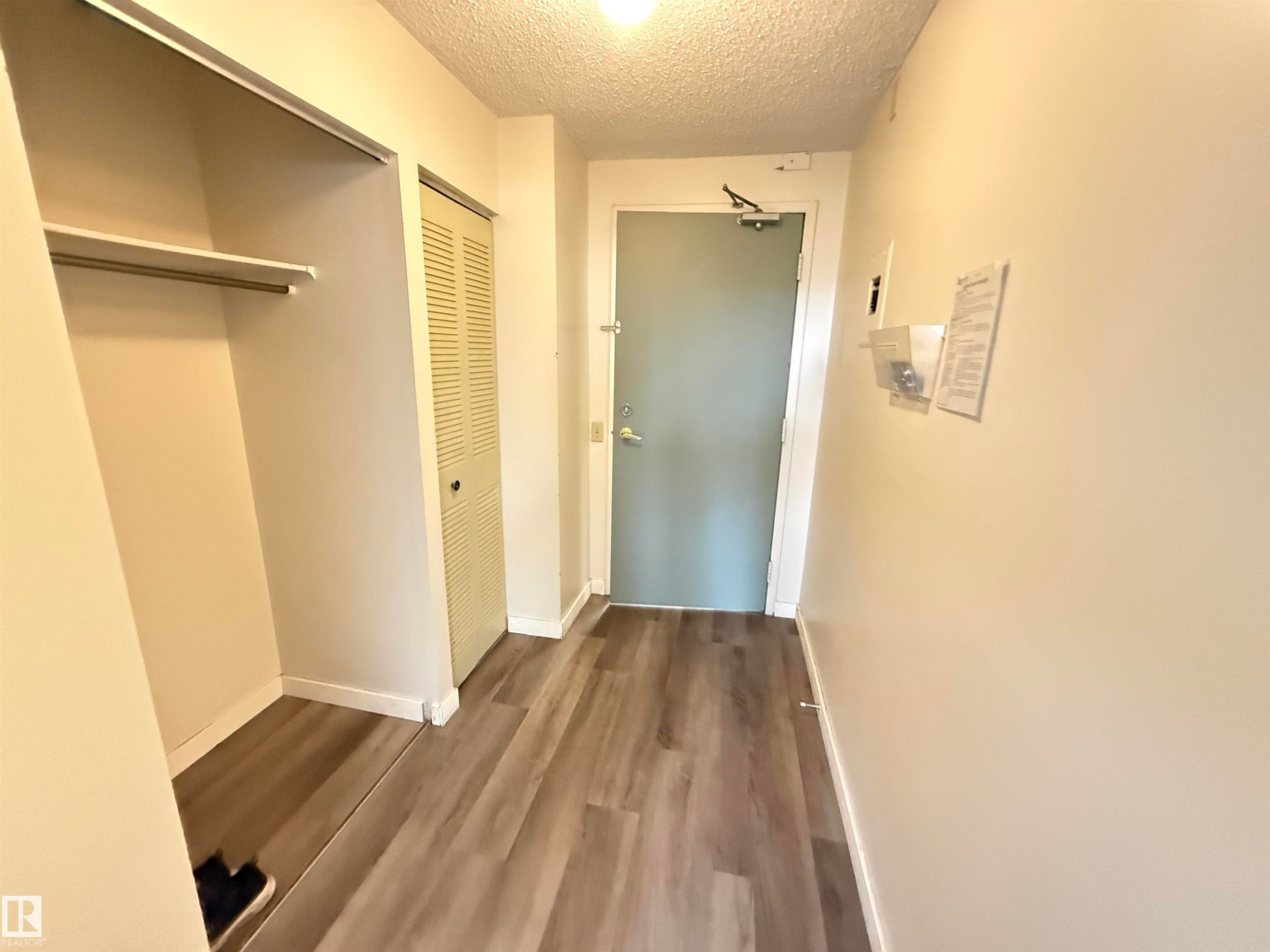 Entryway featuring wood-finish flooring, white baseboards, and a recessed ceiling light - #706 10125 109 St Nw, Edmonton, AB