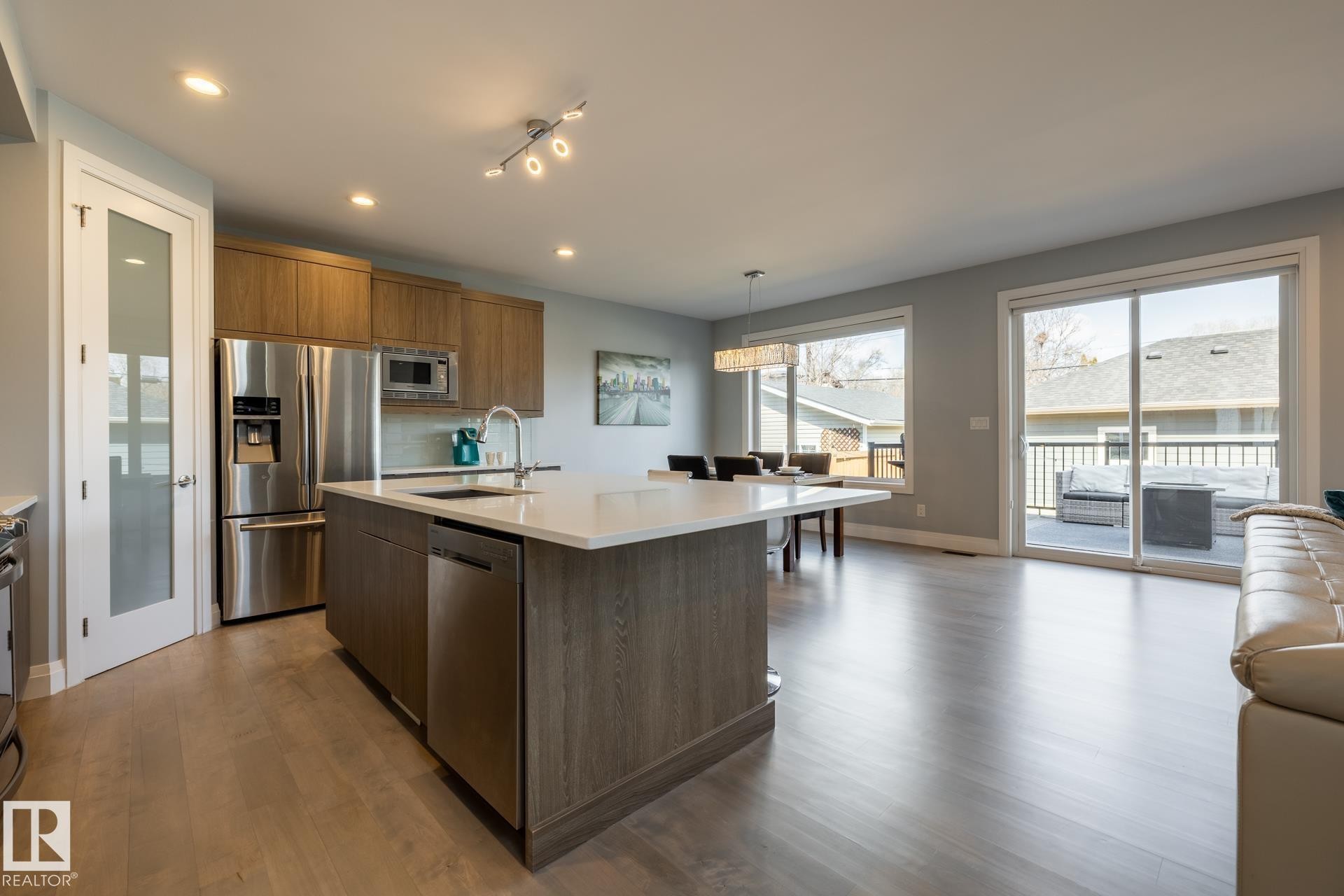 Kitchen with appliances with stainless steel finishes, pendant lighting, a center island with sink, dark wood-style floors, and modern cabinets - 10936 71 Avenue, Edmonton, AB
