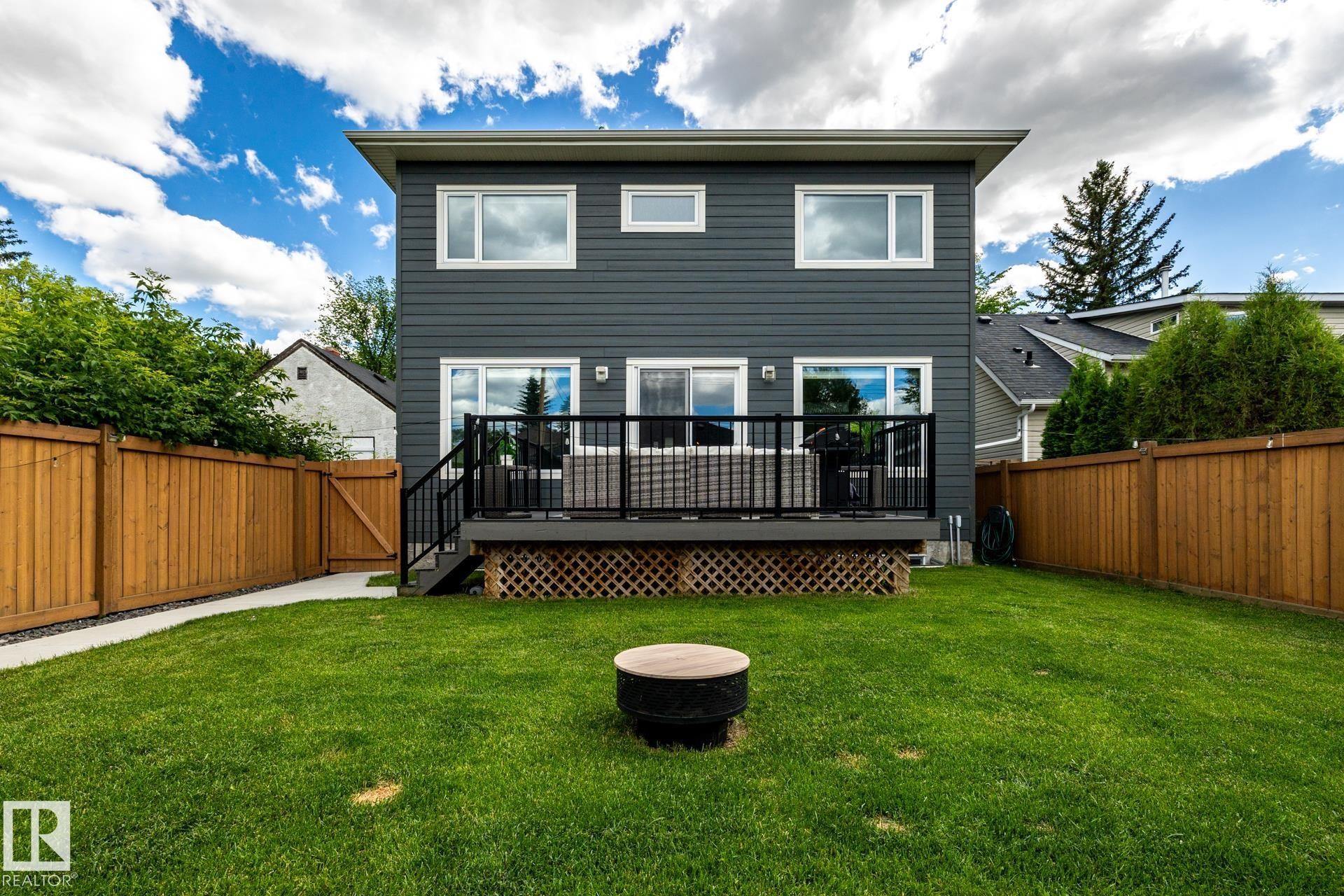 Expansive backyard featuring a lush lawn, a composite deck with black metal railing, and a privacy fence - 10936 71 Avenue, Edmonton, AB