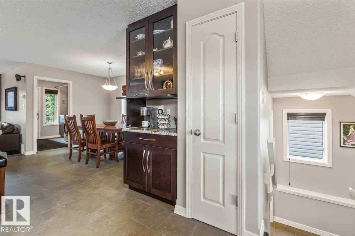 Kitchenette area featuring dark wood-finish cabinetry, a granite-finish countertop, and glass-front upper cabinets - 1086 Grantham Drive Nw, Edmonton, AB - Indoor