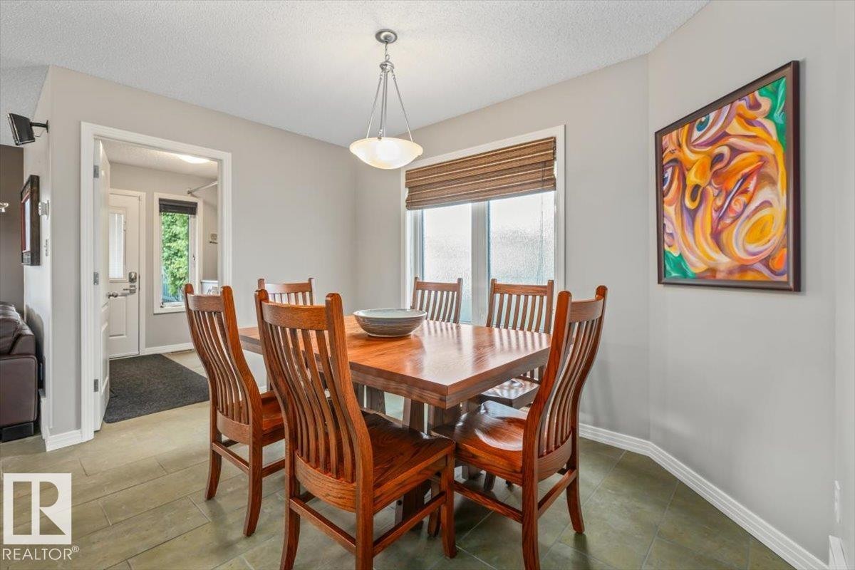 Dining area featuring tile flooring, a wood-finish dining table, and a contemporary pendant light fixture - 1086 Grantham Drive Nw, Edmonton, AB - Indoor Photo Showing Dining Room