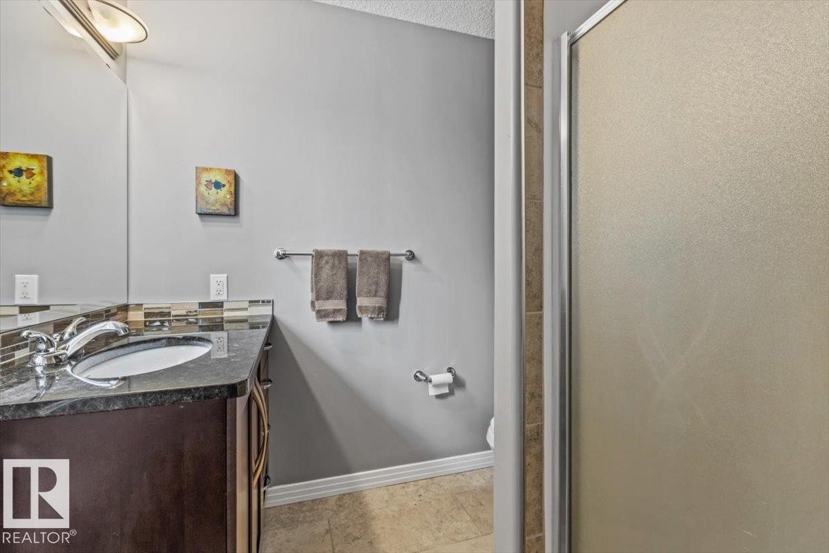 Bathroom vanity featuring a dark wood-finish cabinet with an undermount sink, granite countertop, and mosaic tile backsplash - 1086 Grantham Drive Nw, Edmonton, AB - Indoor Photo Showing Bathroom