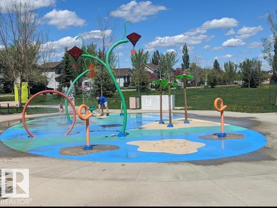 Community splash pad featuring multiple water features, a colorful ground surface, and surrounding green space - 1086 Grantham Drive Nw, Edmonton, AB - Outdoor With In Ground Pool