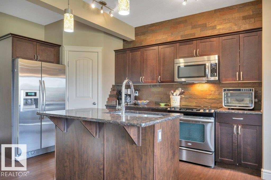 With Stainless Steel appliances, granite counter tops, corner pantry and island - 10 15151 43 Street, Edmonton, AB - Indoor Photo Showing Kitchen With Upgraded Kitchen