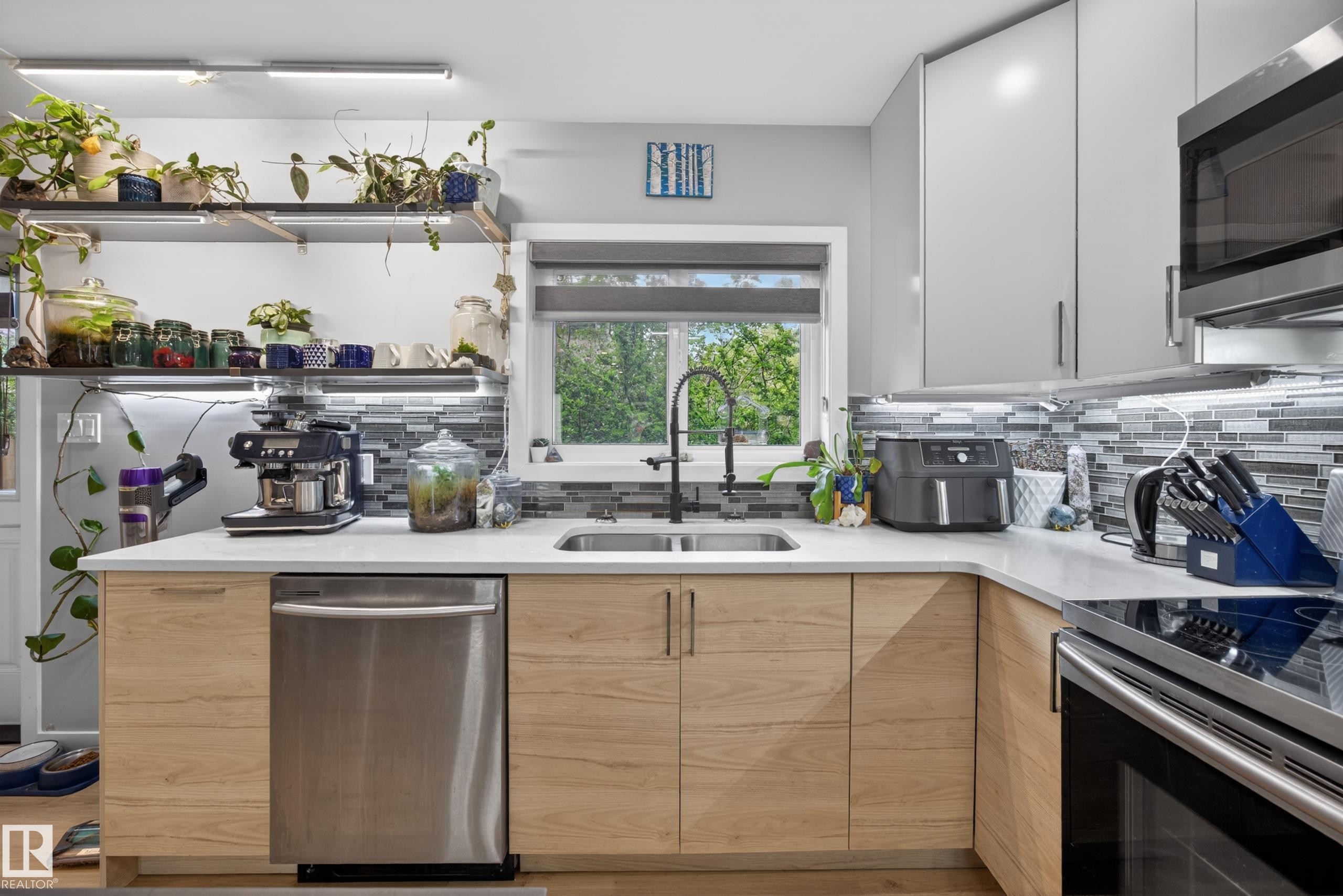 Contemporary kitchen featuring light wood-finish lower cabinetry, sleek grey upper cabinetry, and stainless steel appliances - 12604 116 Avenue, Edmonton, AB