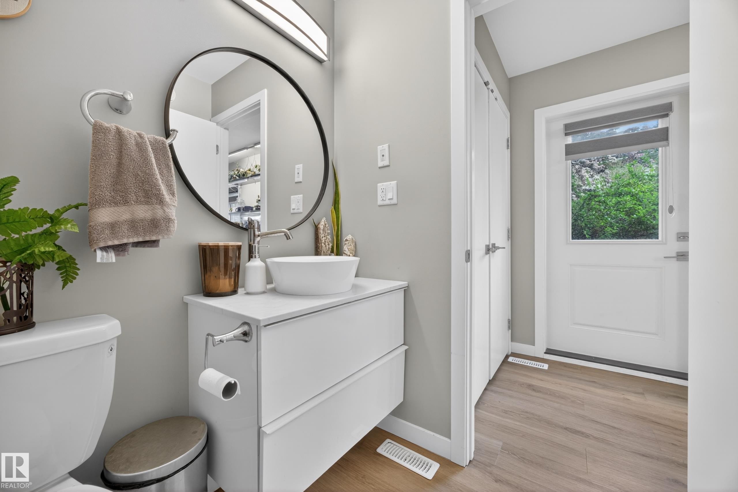 Modern bathroom vanity with a vessel sink, single-handle faucet, and round framed mirror - 12604 116 Avenue, Edmonton, AB