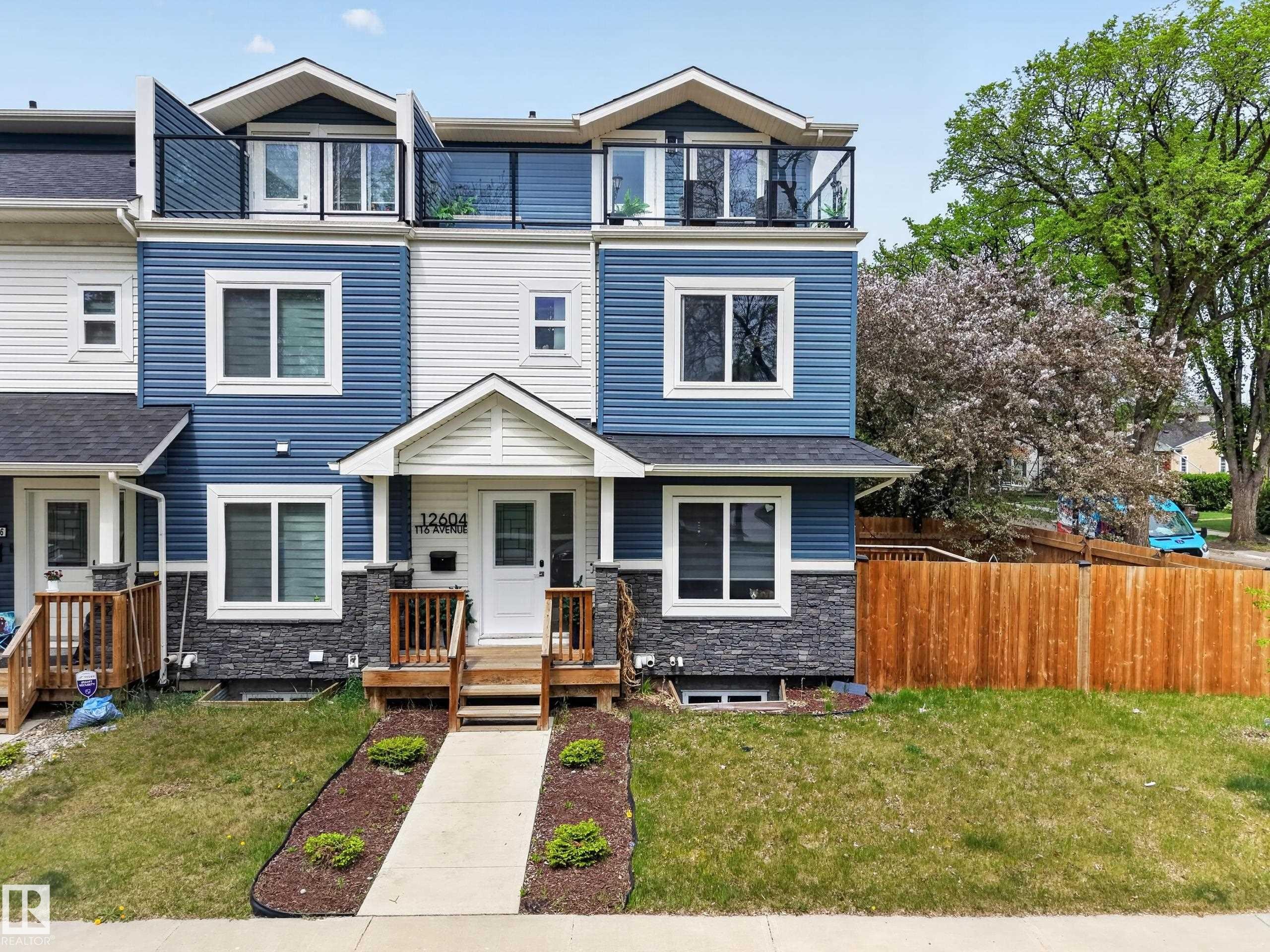 Contemporary townhome with blue siding, white trim, and stone veneer accents - 12604 116 Avenue, Edmonton, AB