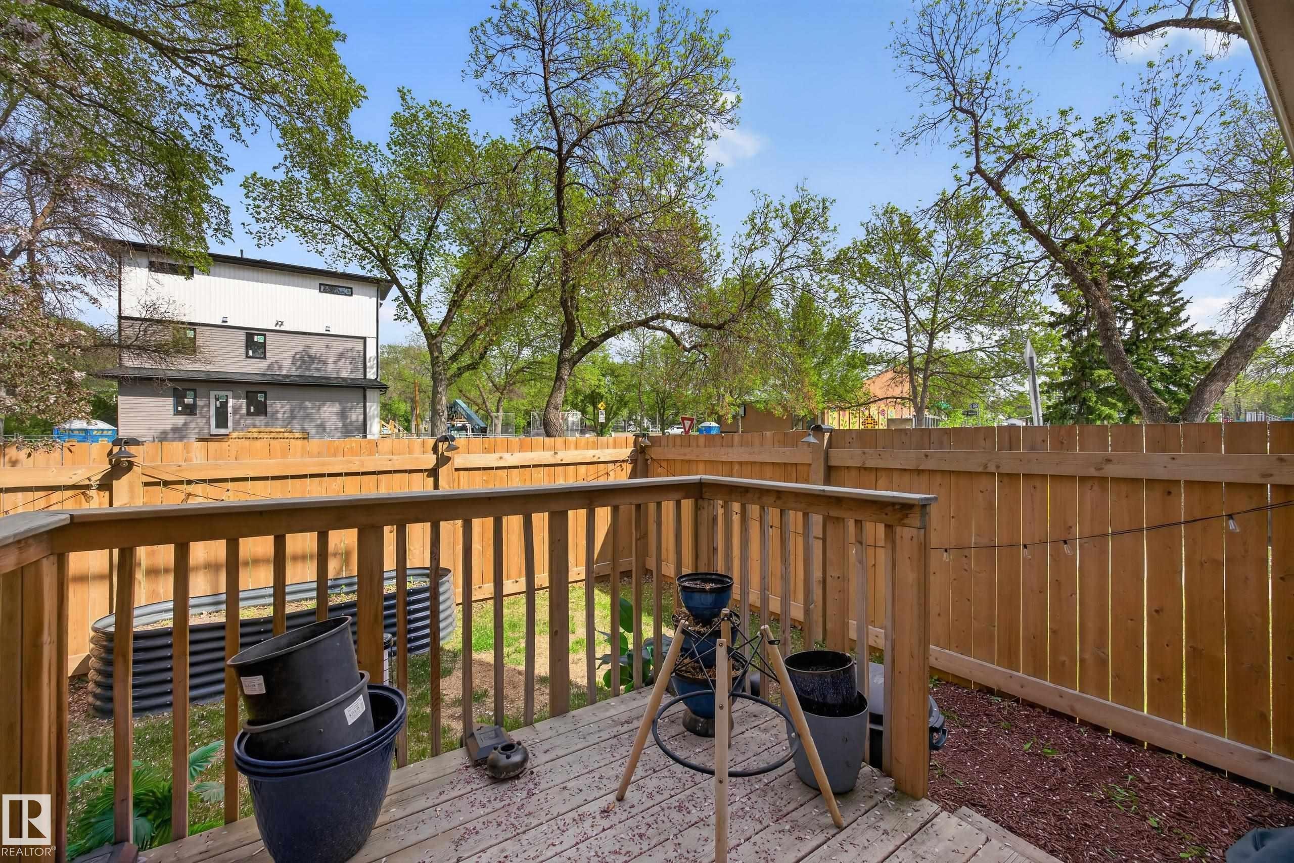 Spacious outdoor deck with natural wood railing, horizontal plank flooring, and a privacy fence - 12604 116 Avenue, Edmonton, AB