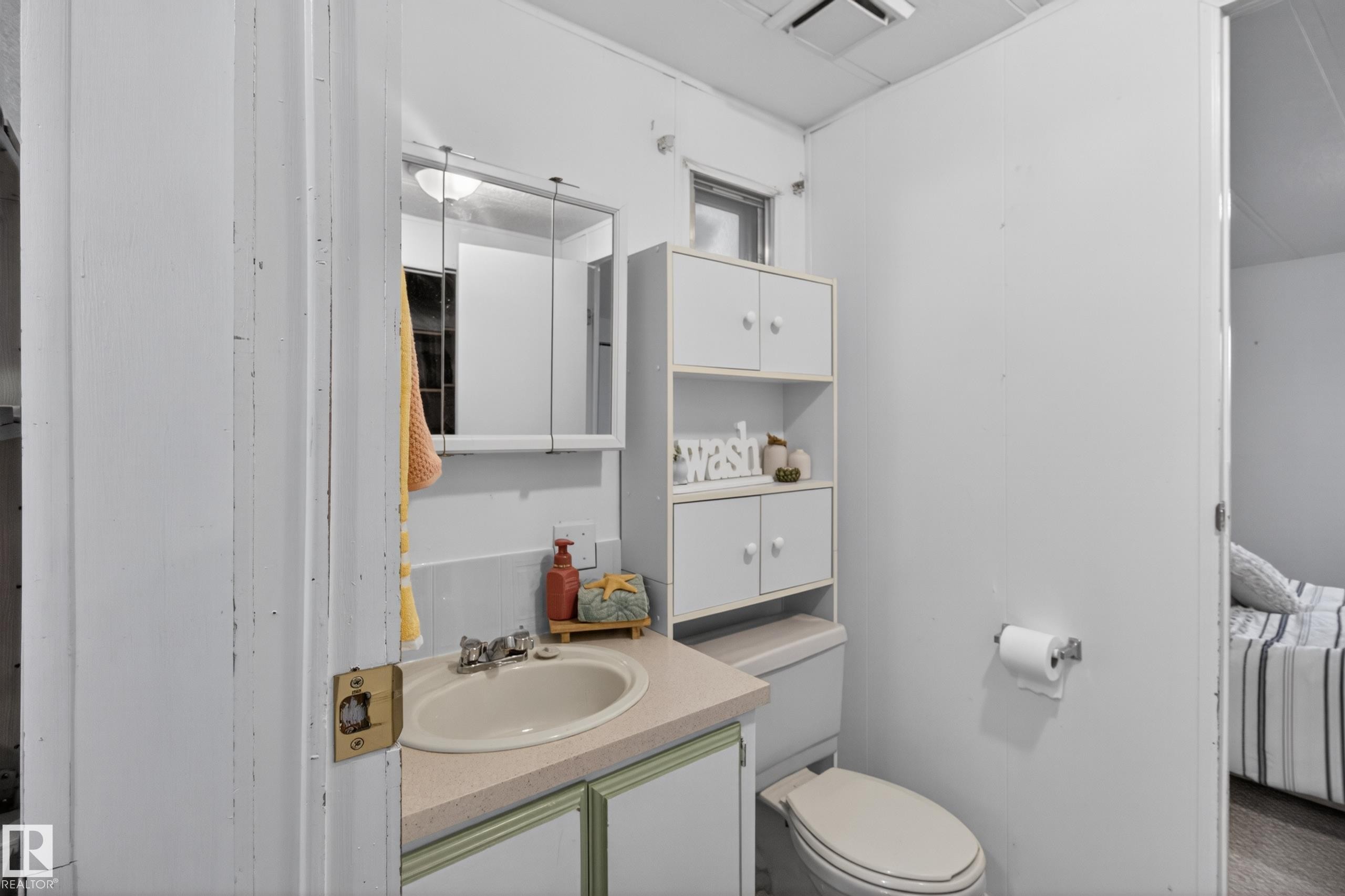 Bathroom featuring a vanity with an integrated sink, a medicine cabinet, a toilet, and overhead storage cabinetry - 21 Willowdale Drive, Edmonton, AB - Indoor Photo Showing Bathroom