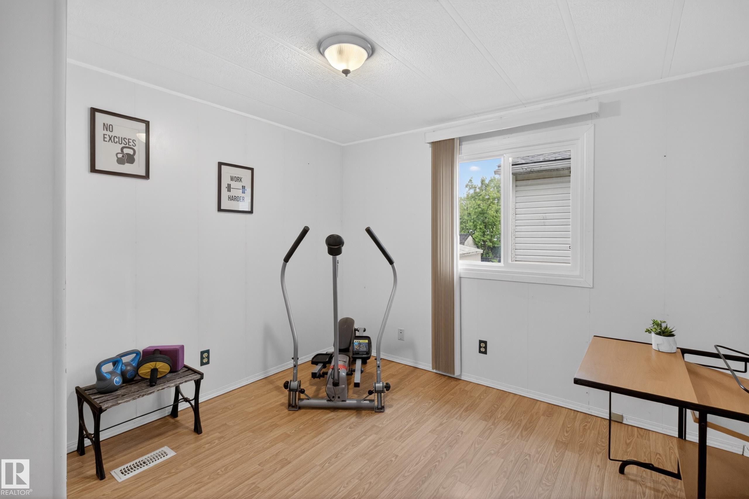 Bright room featuring wood-finish flooring, white walls, and a prominent window with white trim - 21 Willowdale Drive, Edmonton, AB - Indoor