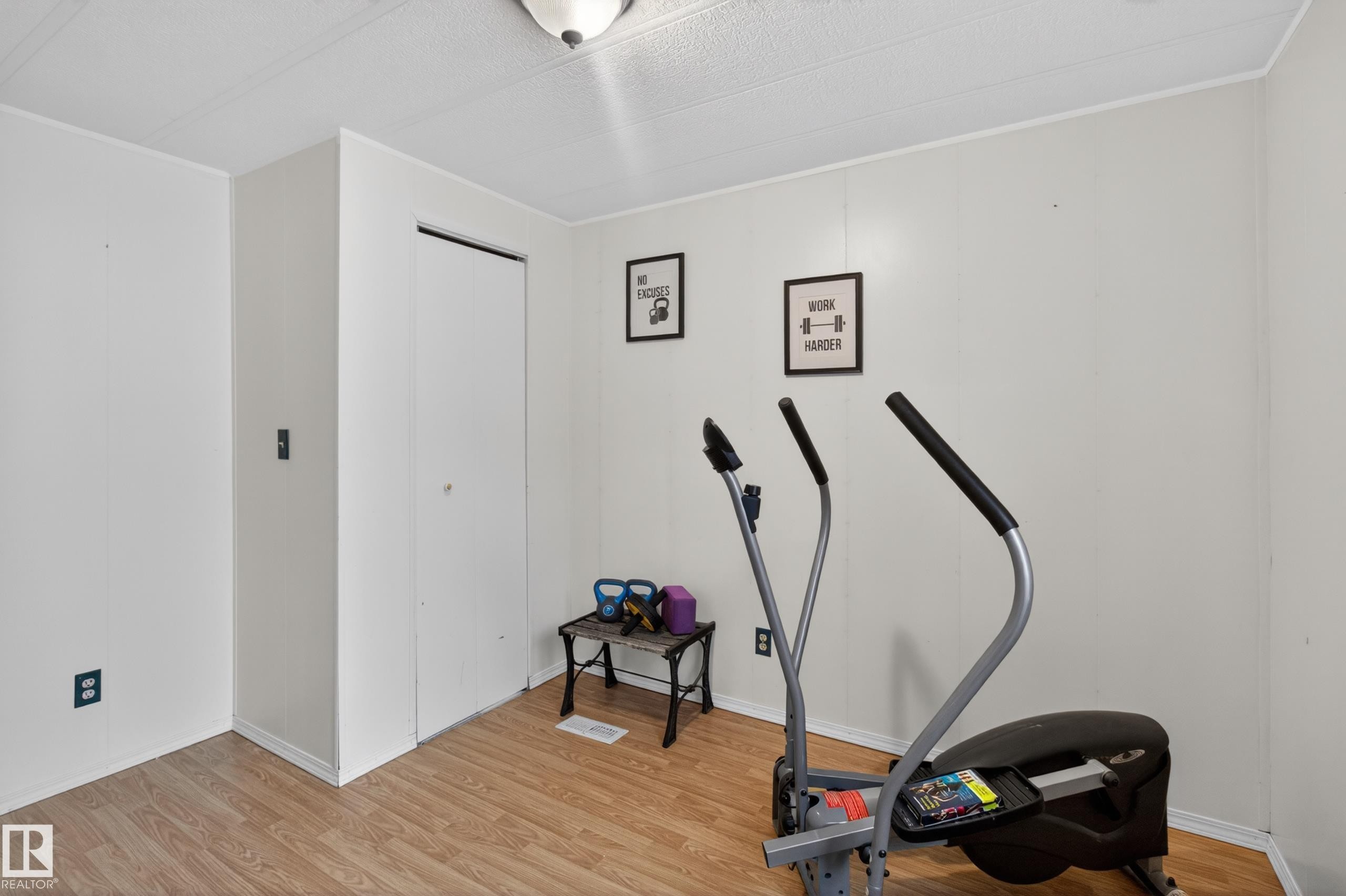 Room featuring wood-finish flooring, white paneled walls, and a white bi-fold closet door - 21 Willowdale Drive, Edmonton, AB - Indoor