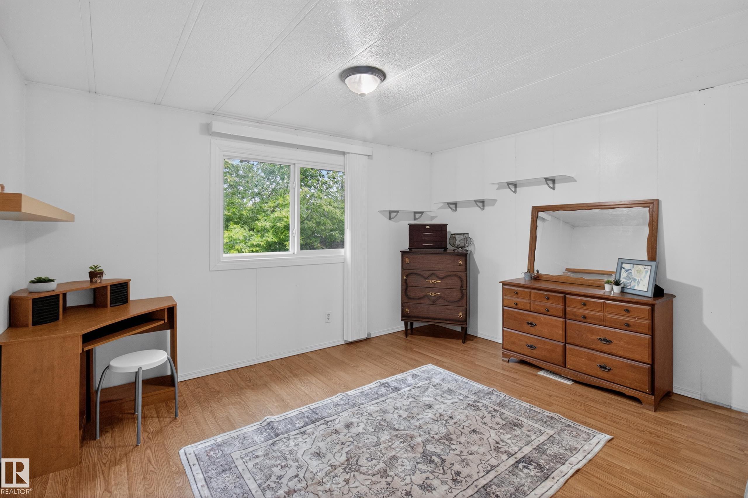 Bright room featuring wood-finish flooring, white paneled walls, and a white ceiling - 21 Willowdale Drive, Edmonton, AB - Indoor