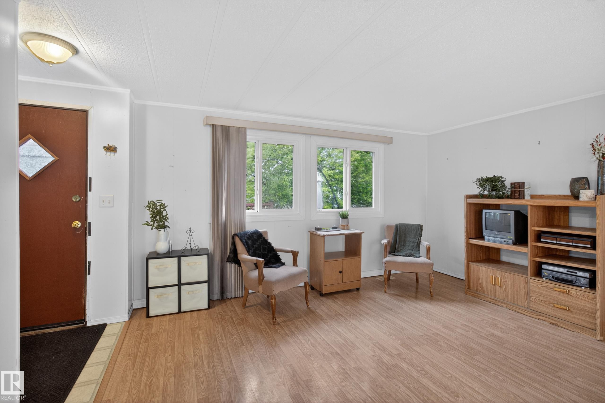Living area featuring wood-finish flooring, white walls, and a large window with natural light - 21 Willowdale Drive, Edmonton, AB - Indoor