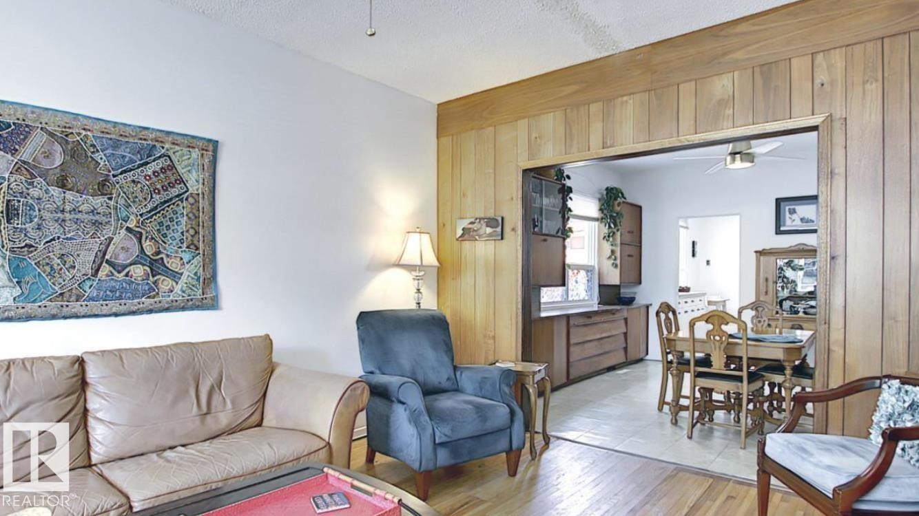 Living area with wood-finish flooring and a white painted wall - 10017 113 Street, Edmonton, AB