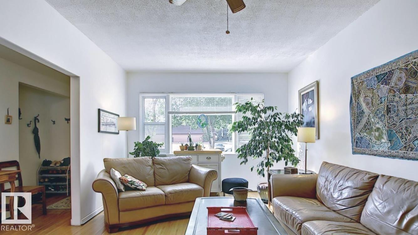 Living area with hardwood flooring, white painted walls, and a ceiling fan - 10017 113 Street, Edmonton, AB