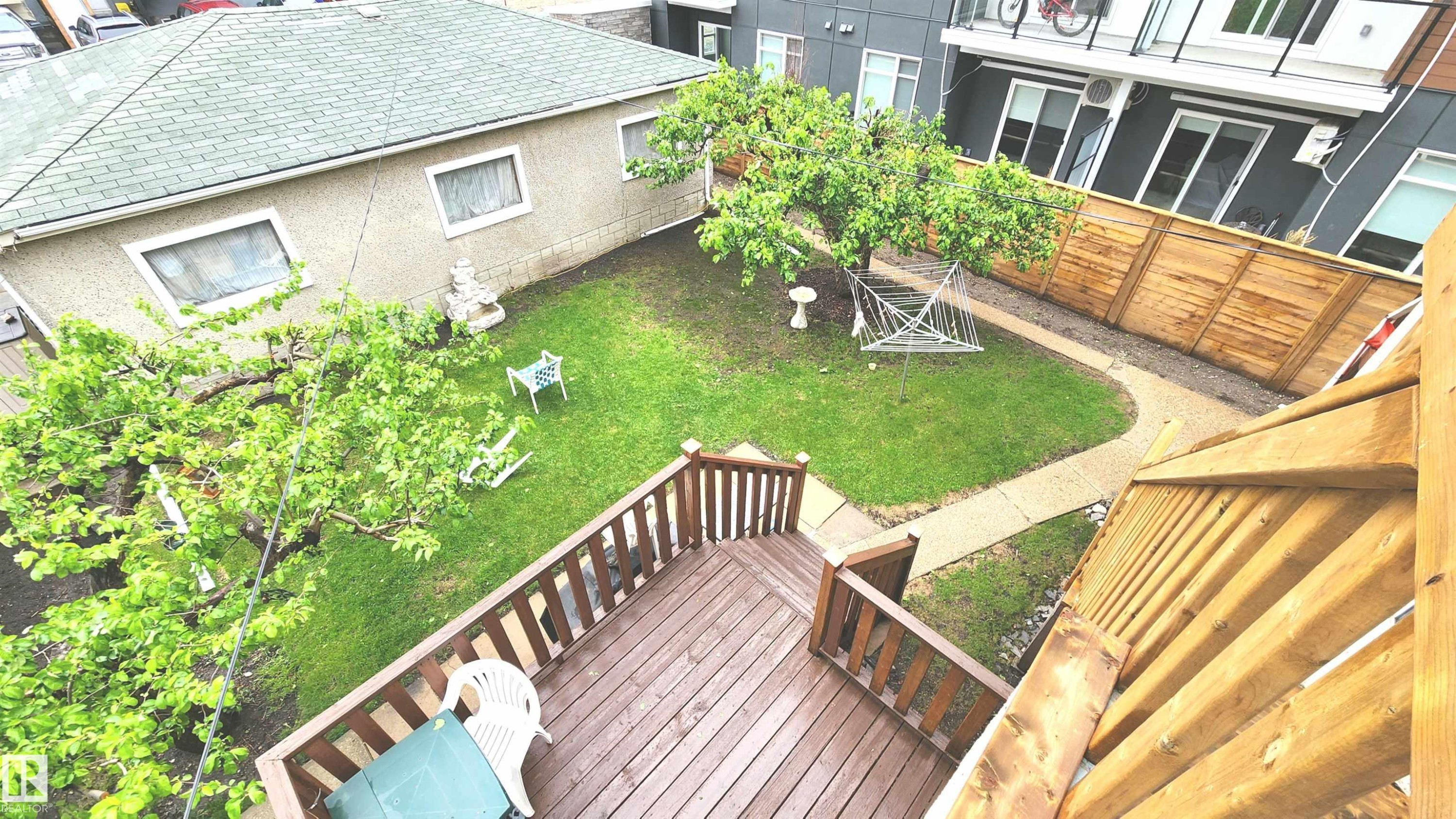 Wood-finish deck with railings overlooking a green lawn - 10017 113 Street, Edmonton, AB