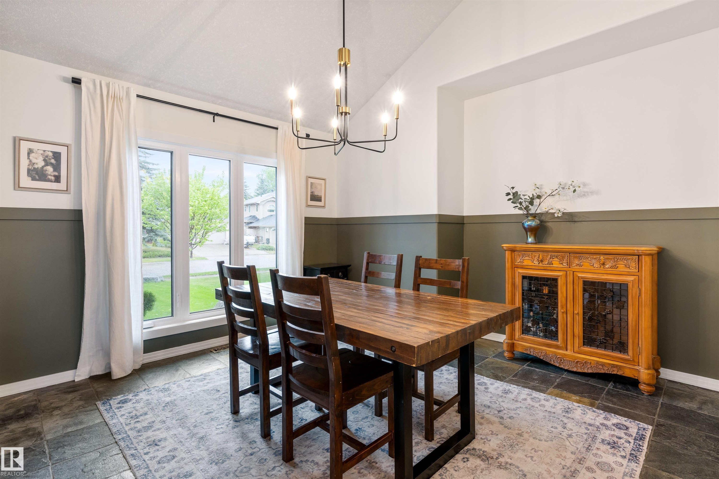 Vaulted ceilings enhance this dining space featuring a modern chandelier, large picture window, and slate-look tile flooring - 10 Everest Crescent, St. Albert, AB