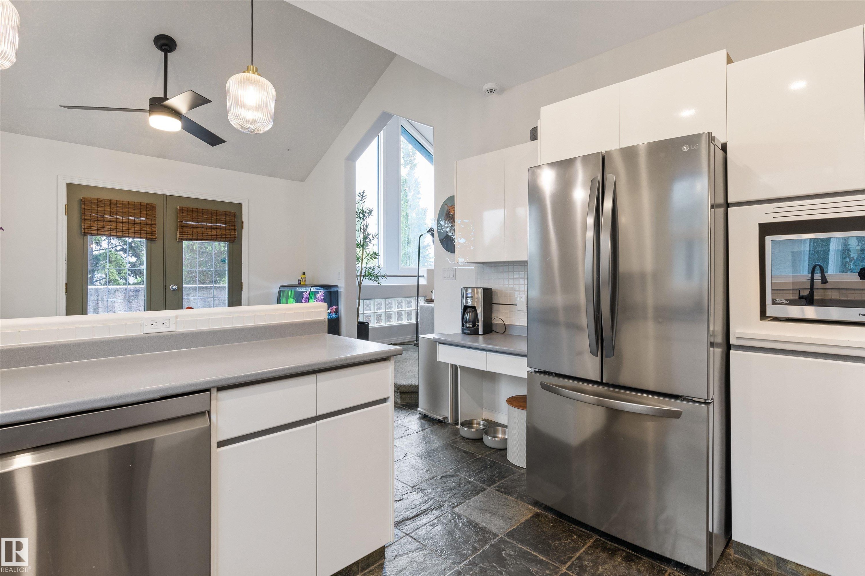 Kitchen featuring dark slate floor tiles, white flat-panel cabinetry, stainless steel French door refrigerator, built-in microwave, and light gray countertops - 10 Everest Crescent, St. Albert, AB