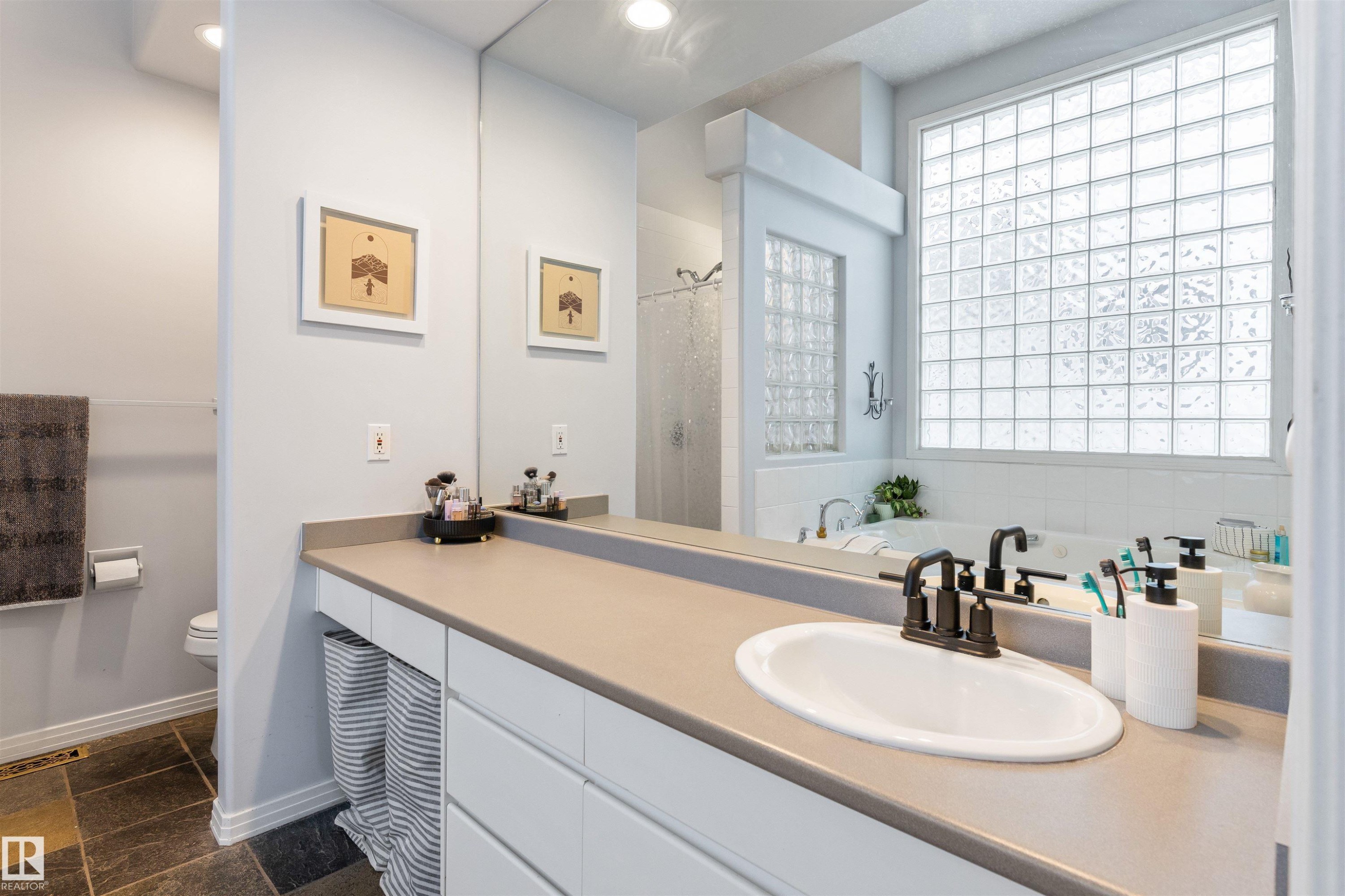 Bathroom featuring a spacious vanity with an integrated sink, dark bronze faucet, and expansive mirror - 10 Everest Crescent, St. Albert, AB
