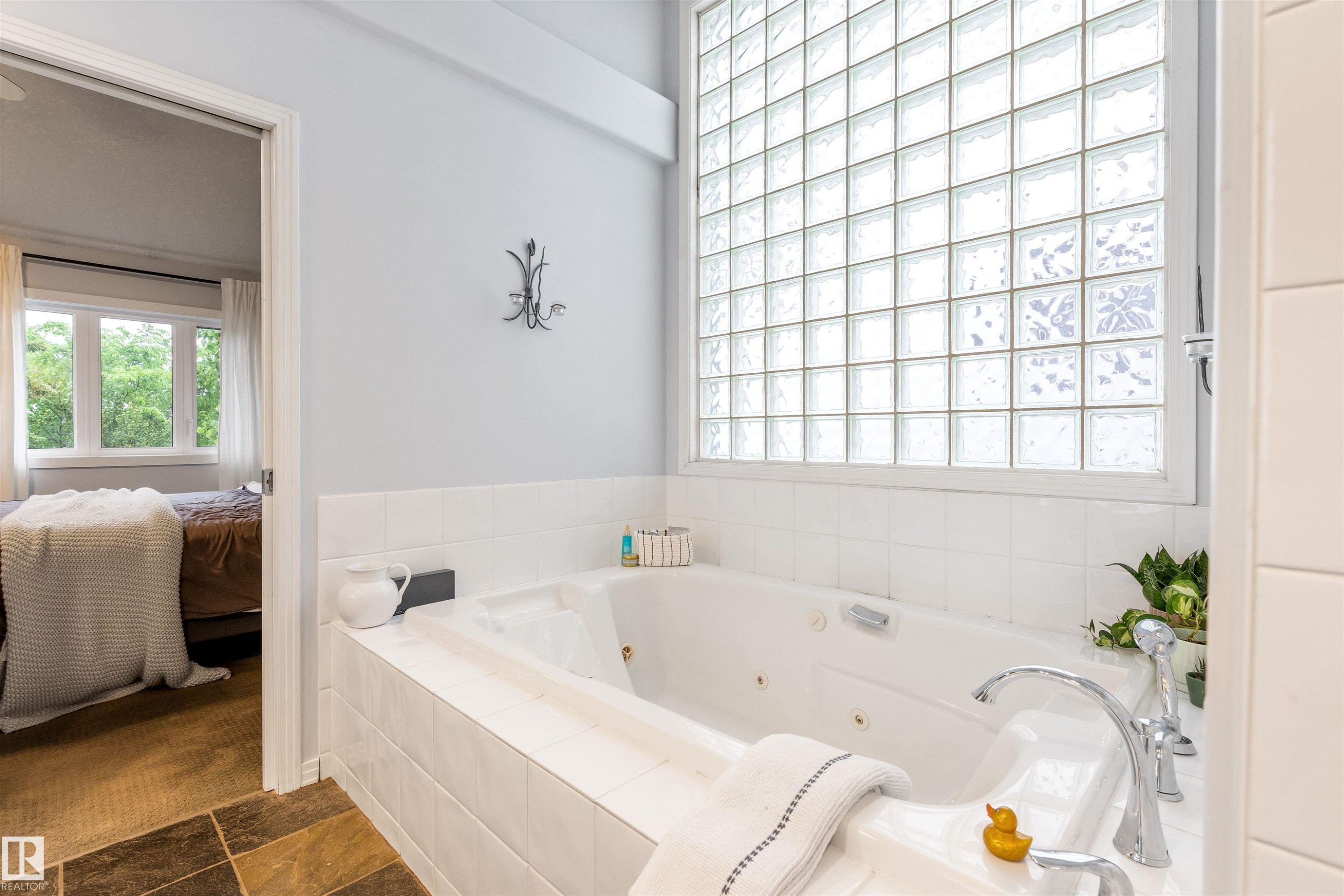 Soaking tub with white tile surround, chrome fixtures, and a glass block window - 10 Everest Crescent, St. Albert, AB